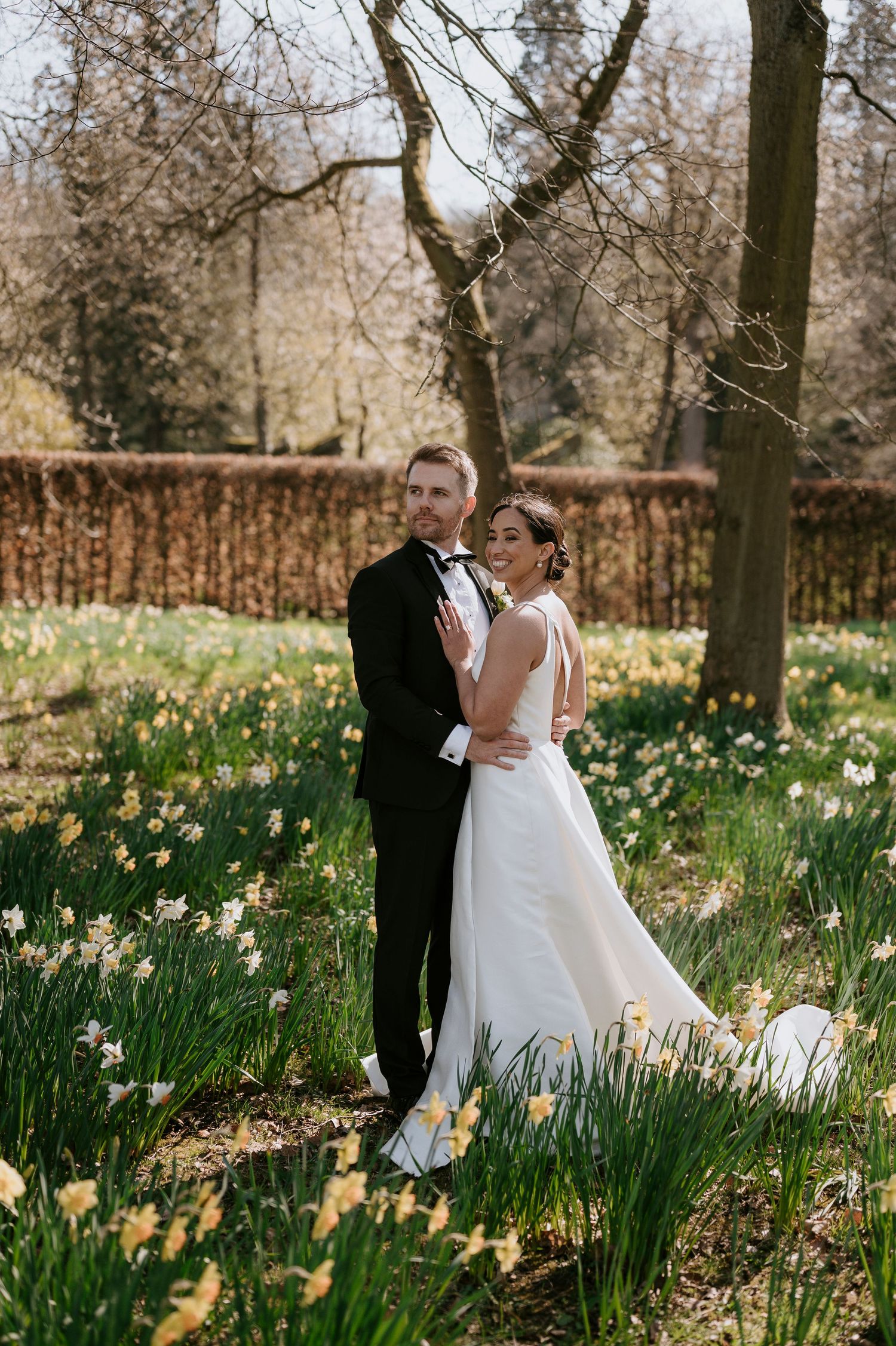 A couple shares romantic moments in a spring garden filled with blooming daffodils and trees.
