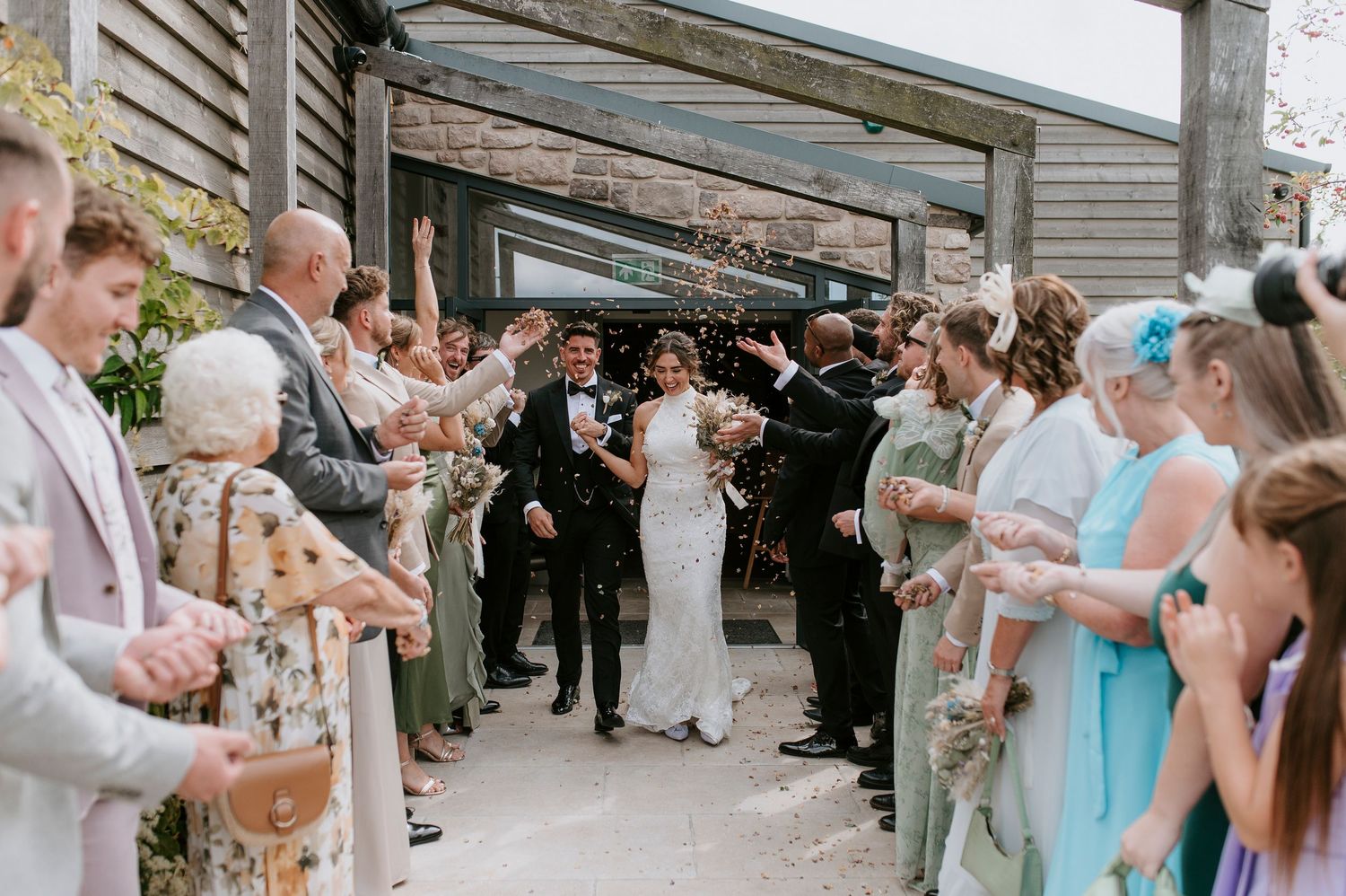 Wedding guests stand in line at an outdoor venue for a receiving line during a summer celebration.