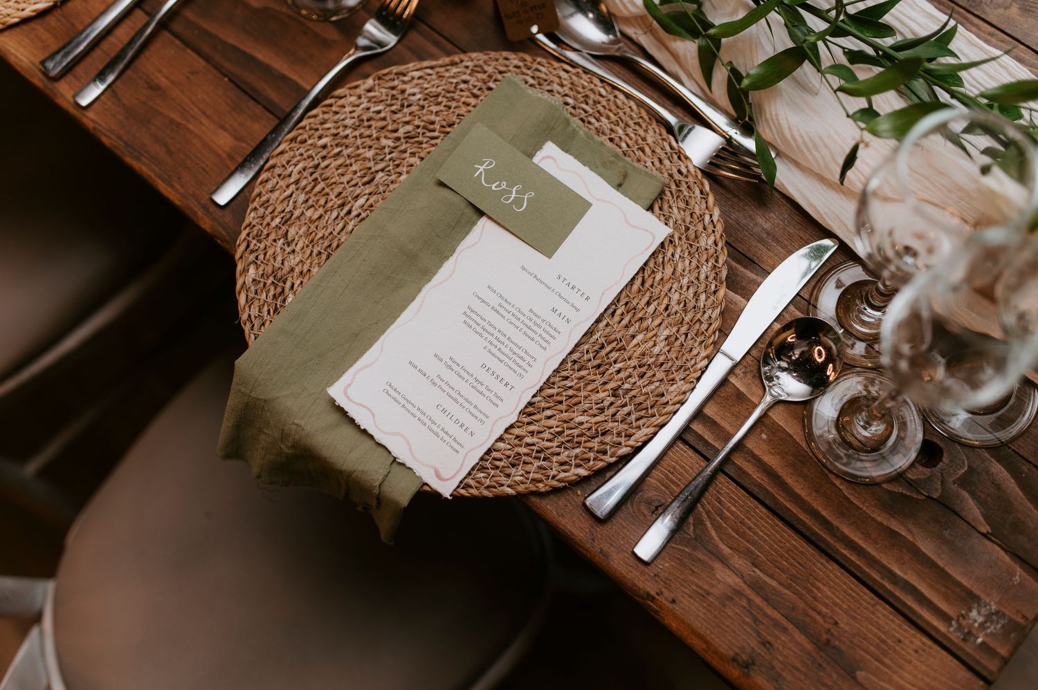 Elegant wedding reception table setting with woven charger plates, white linens, and delicate floral centerpieces.