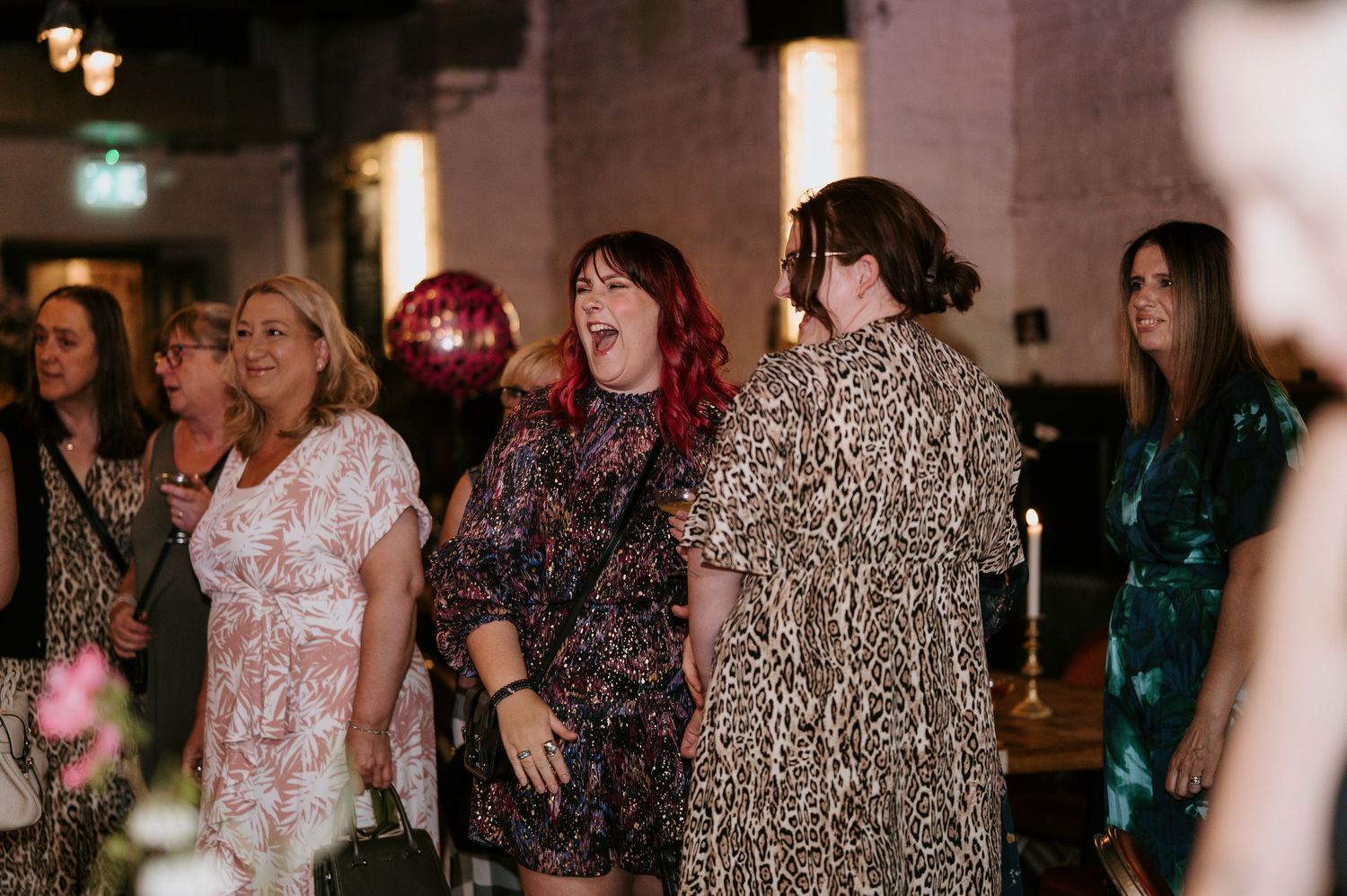 A group of party guests in sparkly dresses dancing and enjoying themselves at an evening celebration.