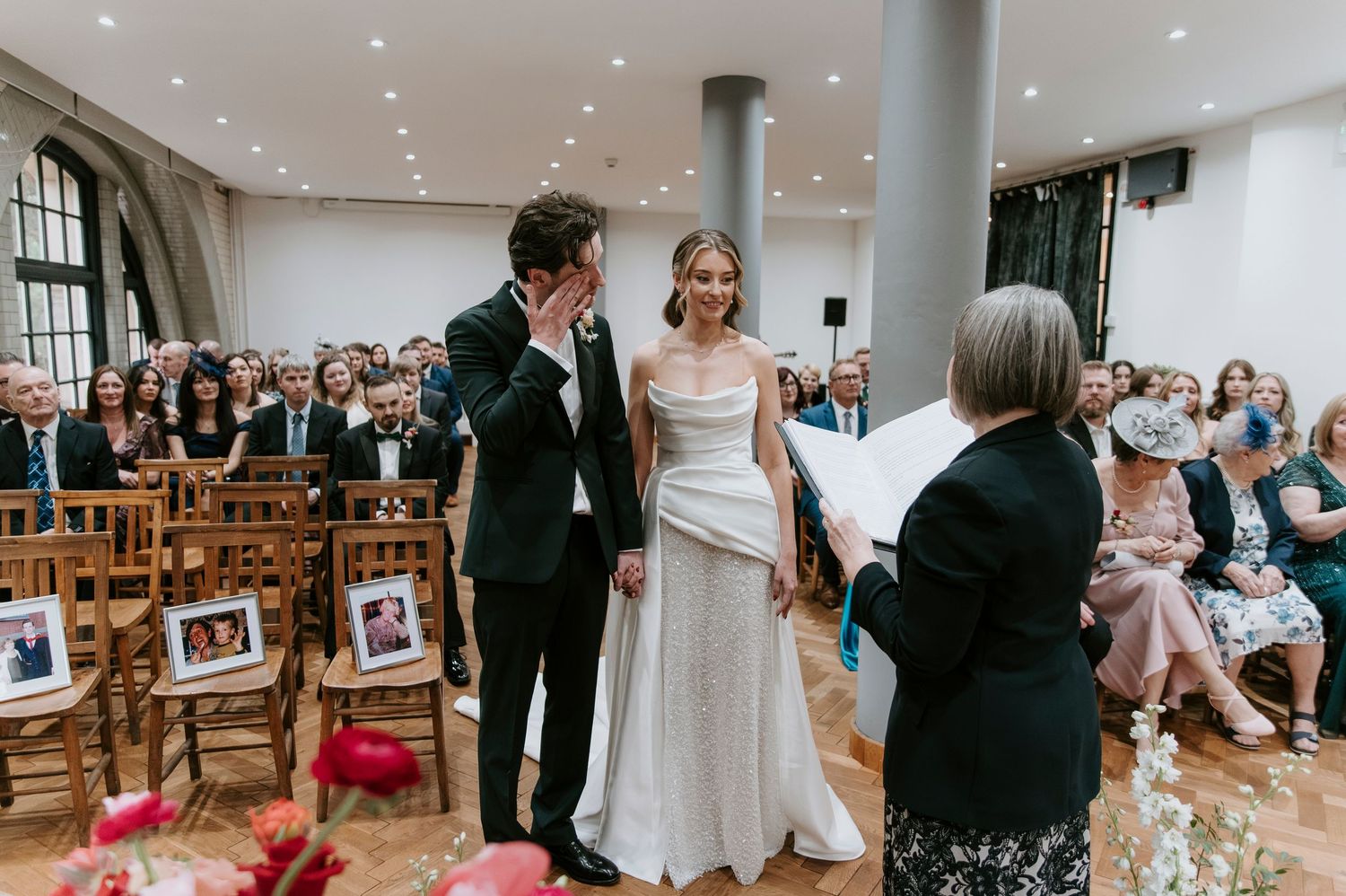Wedding ceremony in progress at a modern indoor venue with guests seated in rows.
