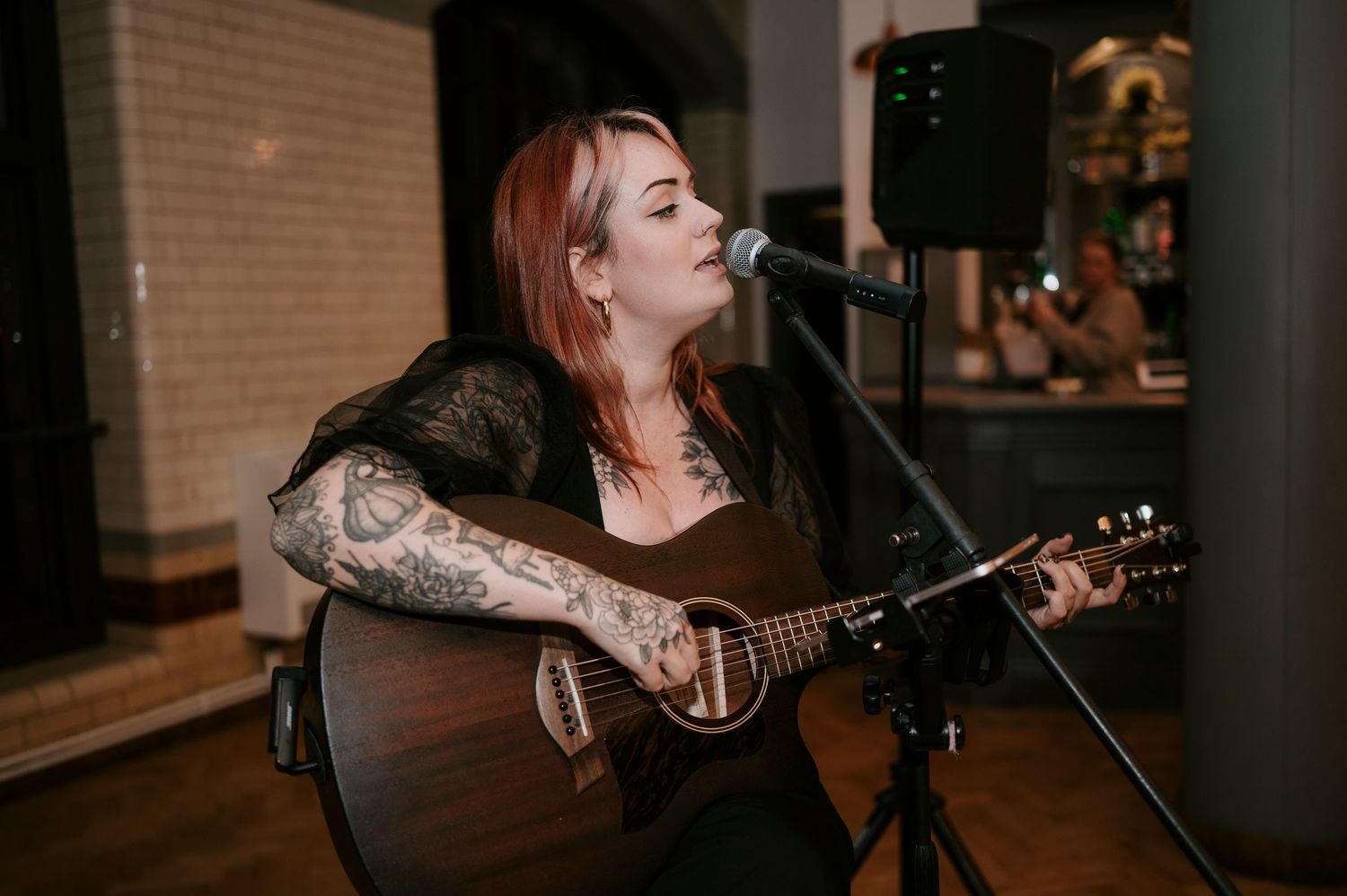 A musician performs with an acoustic guitar in a dimly lit venue during an intimate performance.