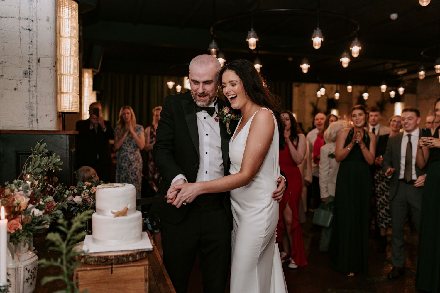 Romantic evening wedding reception with string lights illuminating a rustic brick-walled space.