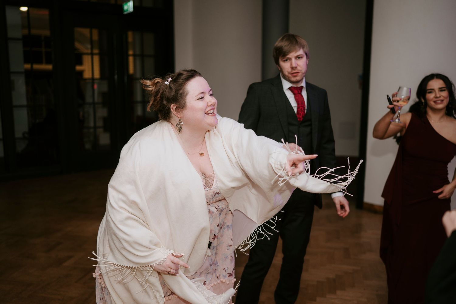 Wedding guests dancing and mingling during evening reception in a contemporary space.