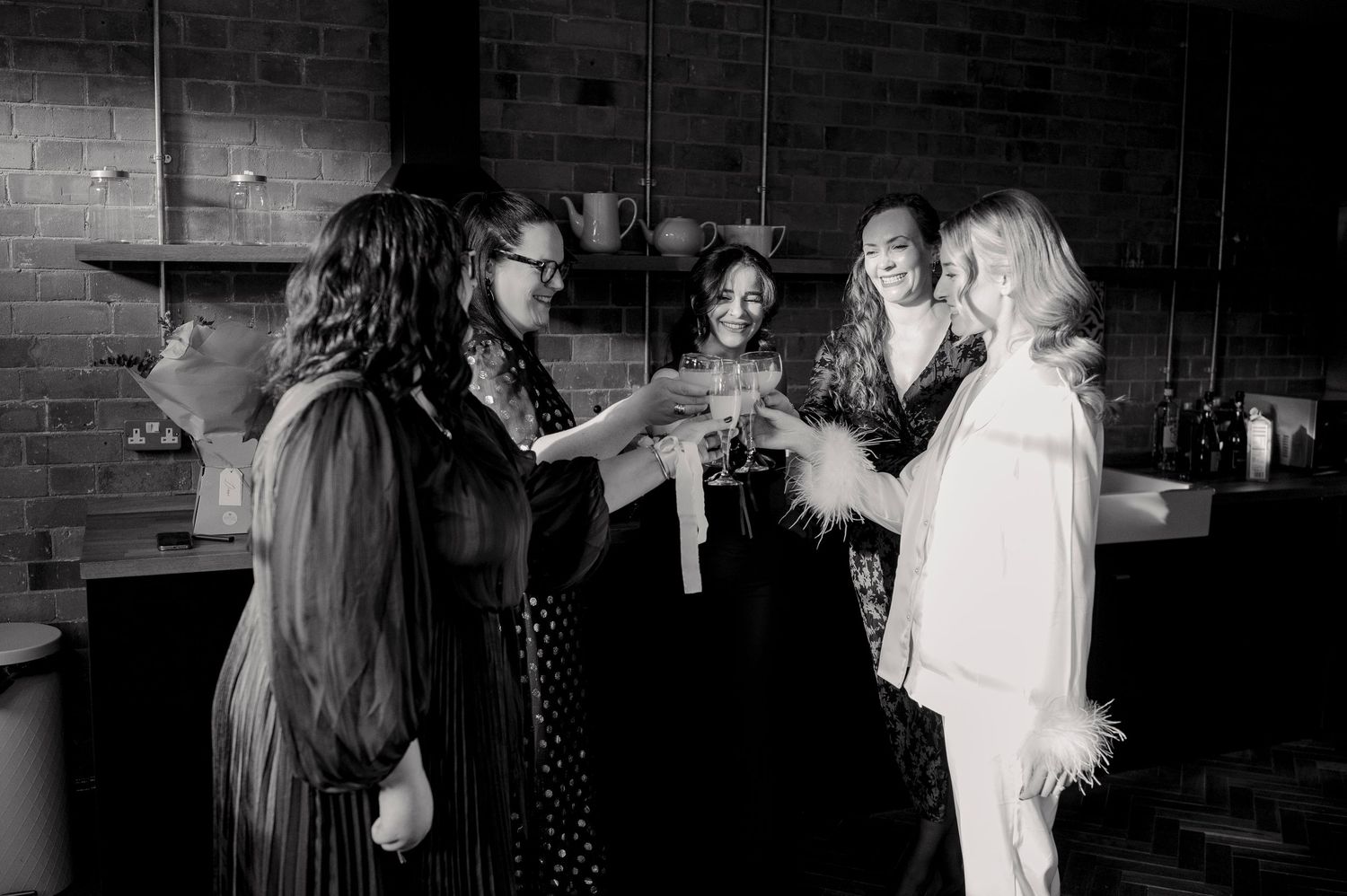 A group of people dancing and socializing at a party with dark brick walls in the background.