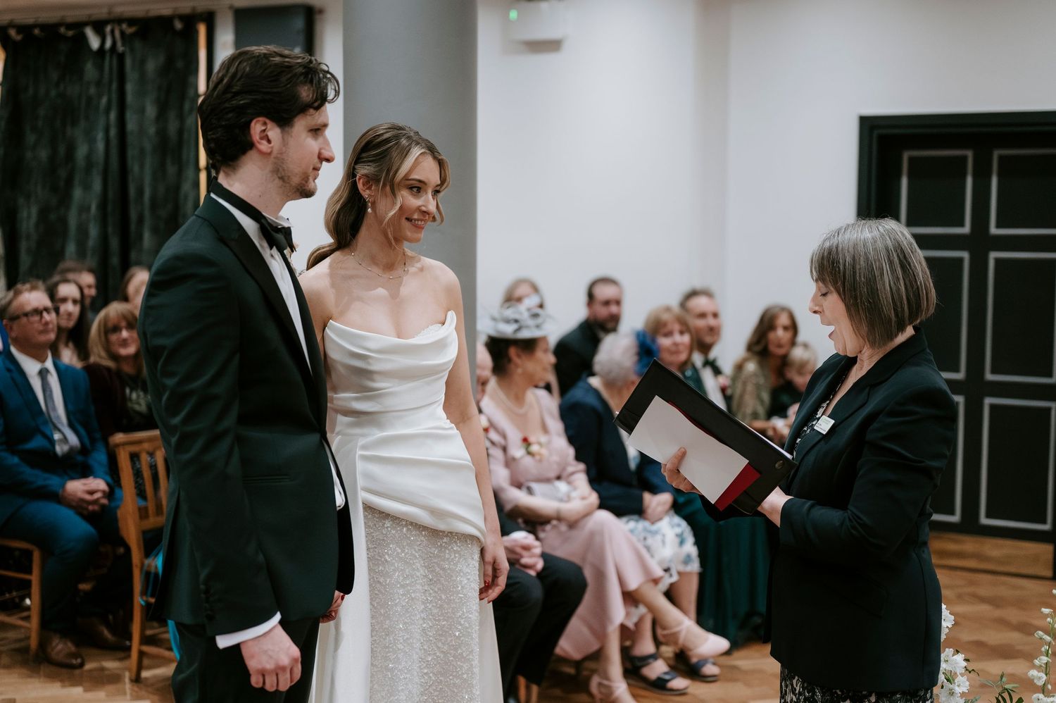 A couple shares their first dance at their wedding reception while guests watch from the sides of the dance floor.
