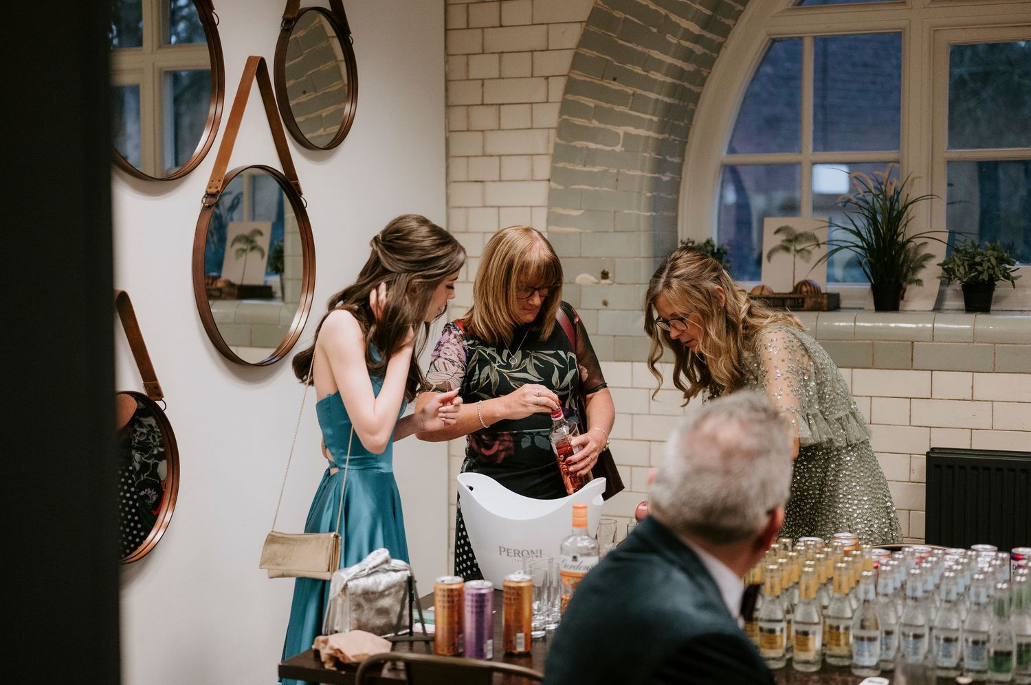 Wedding reception guests mingle and celebrate in elegant indoor venue with mirrors.