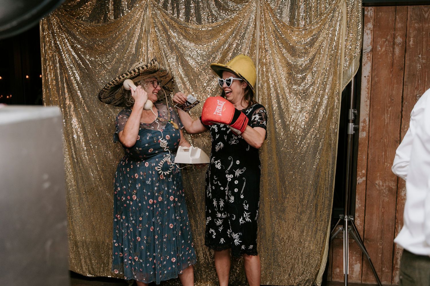 People dancing and celebrating at a wedding reception with a sparkly gold sequin backdrop.