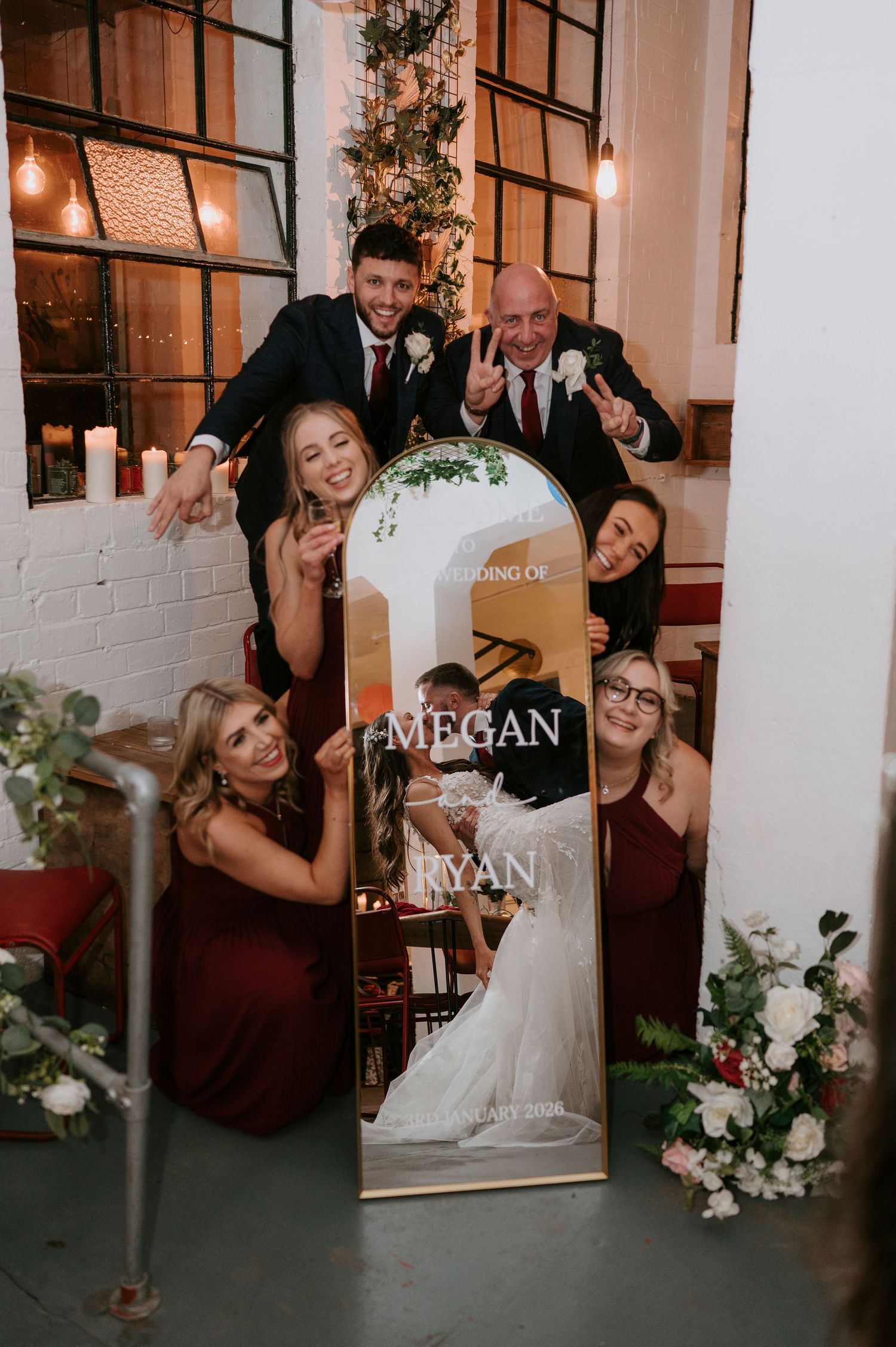 Wedding party poses with Megan and Ryan's elegant gold arch mirror sign at their reception venue.