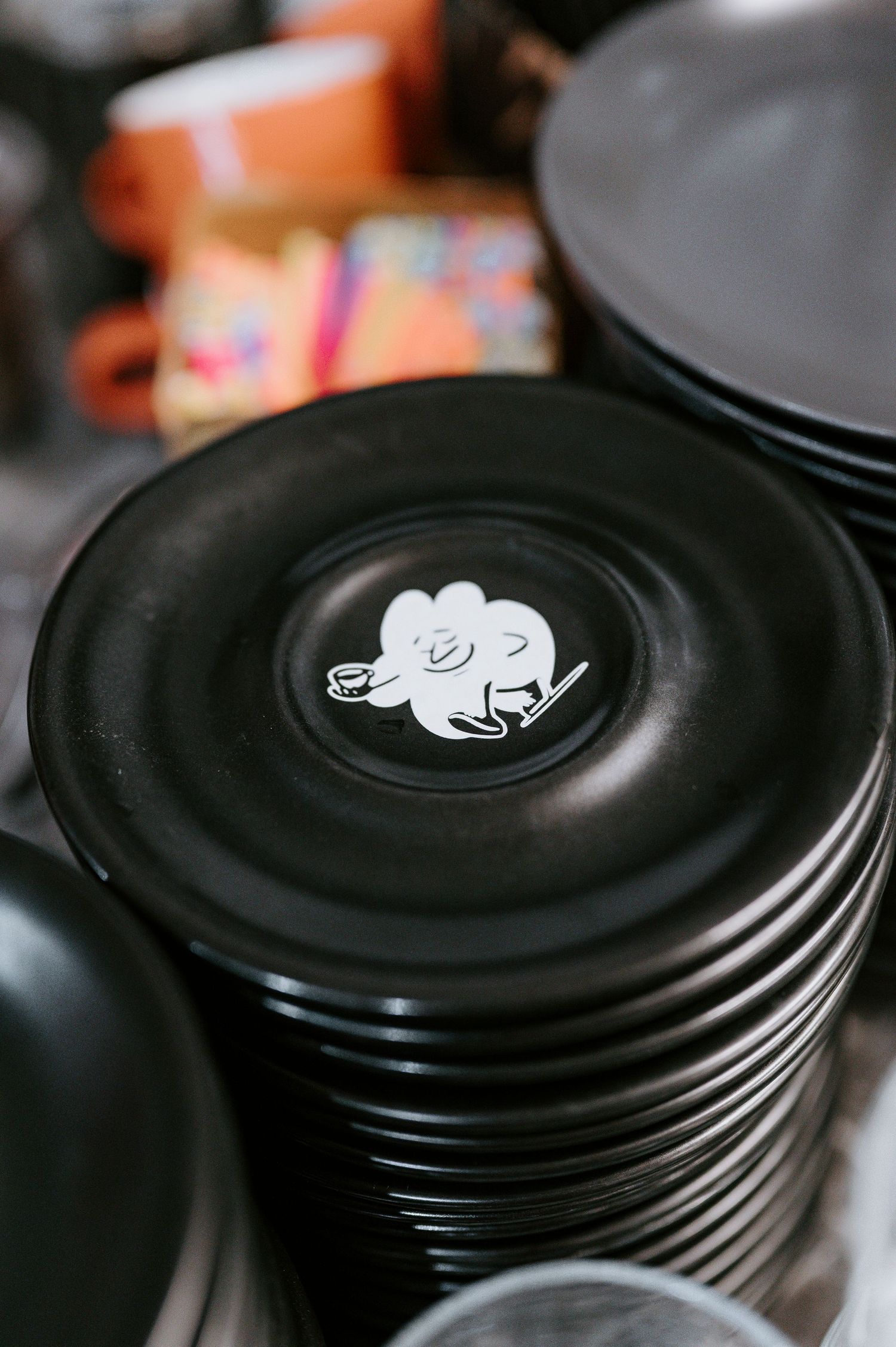 Stack of black coffee cup lids with cute cartoon animal design on top.