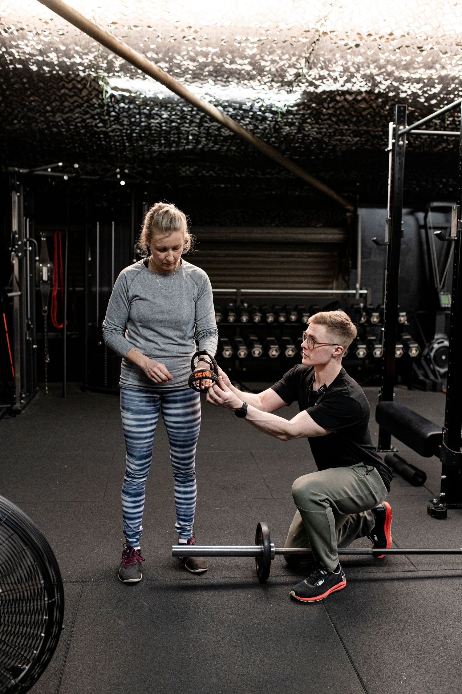 A trainer demonstrates proper form for a cable machine exercise targeting the core and upper body muscles.