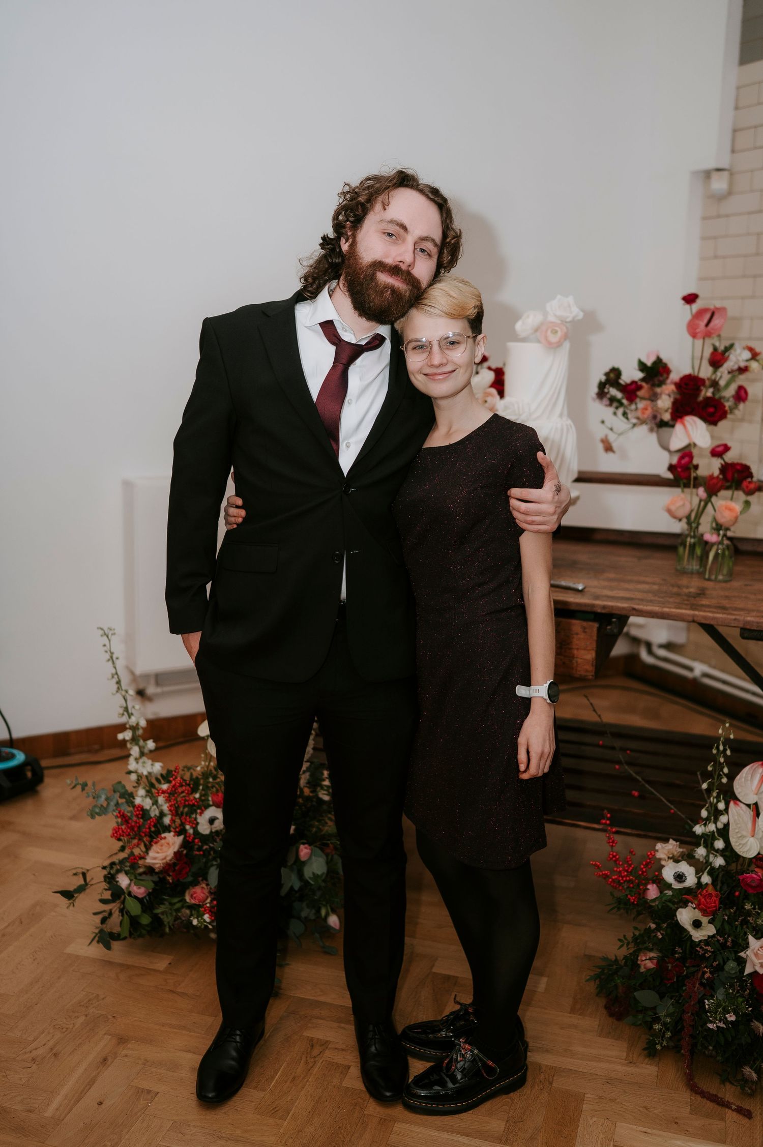 Couple shares intimate moments during their wedding reception against a floral backdrop.