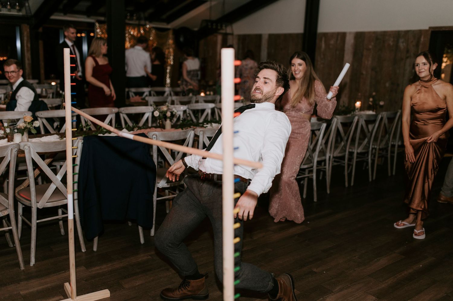 Wedding guests dancing and celebrating on a rustic wooden dance floor at an evening reception.