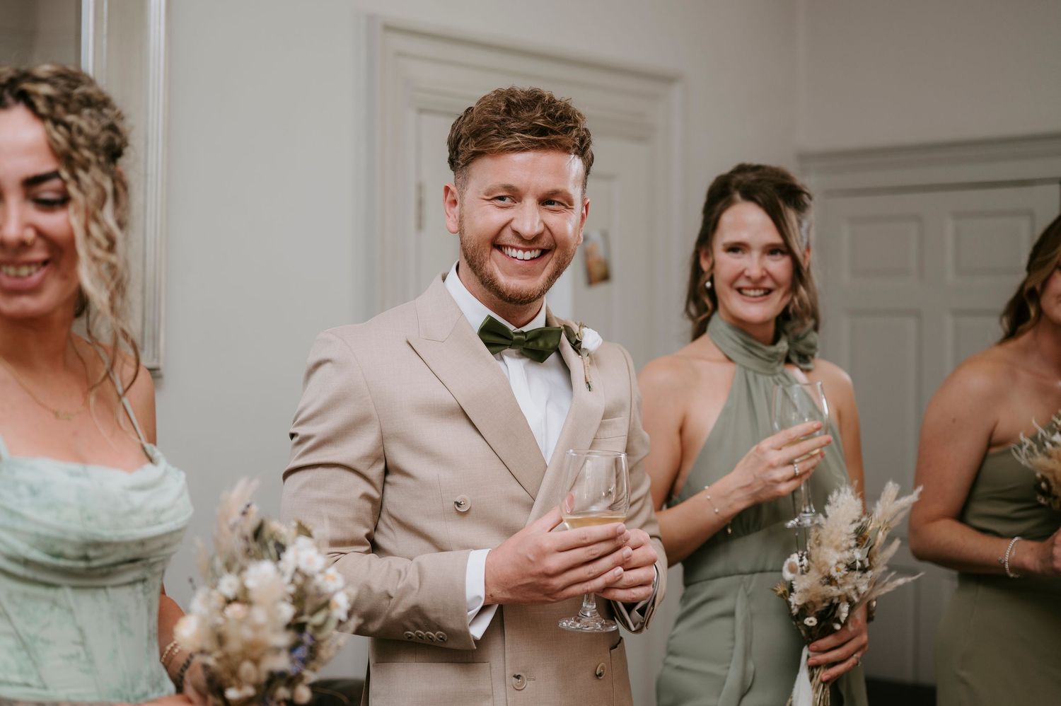 Wedding guests raise champagne glasses in celebration at an elegant indoor reception venue.