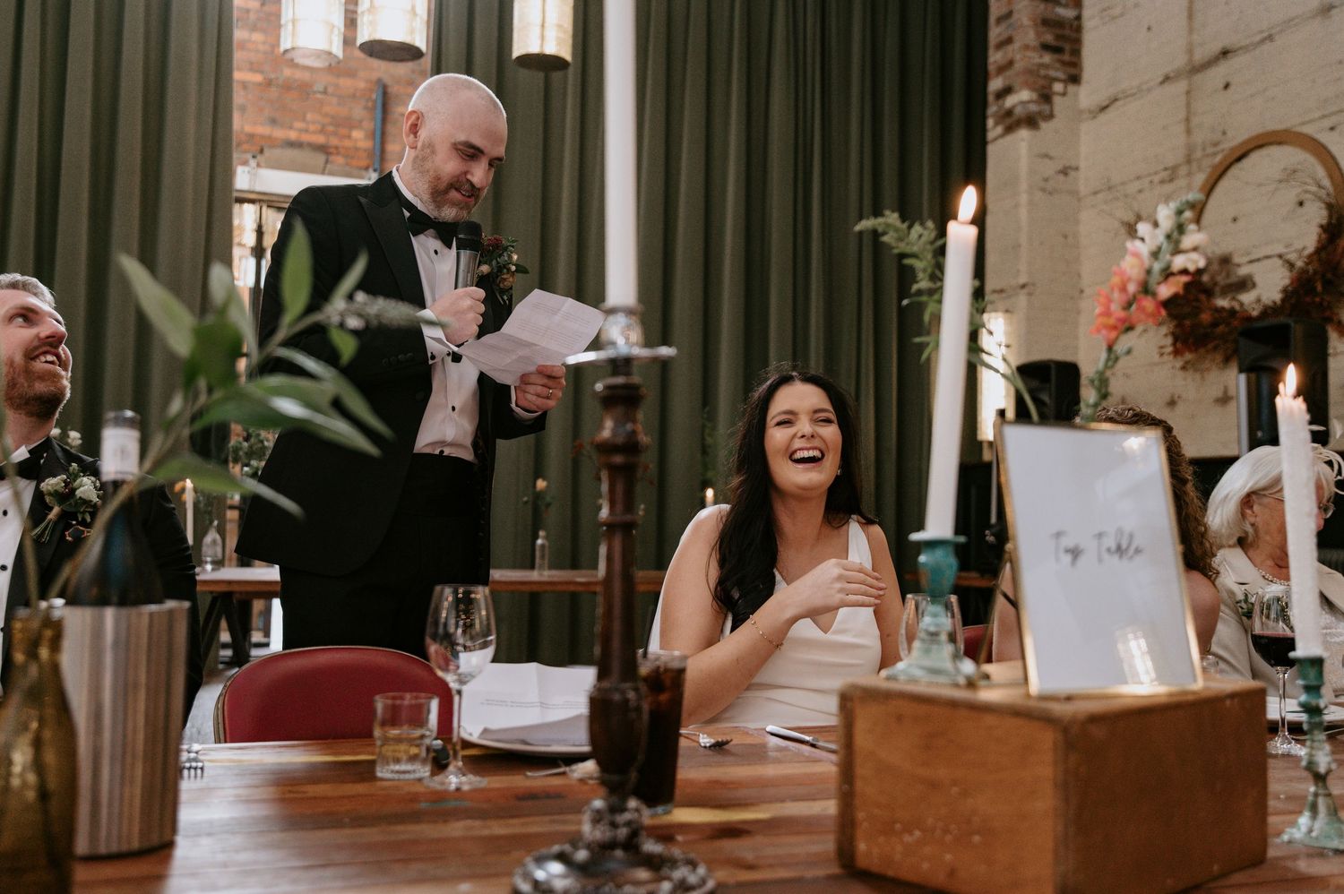 Reception tables set up in an industrial-style venue with brick walls and modern lighting fixtures.