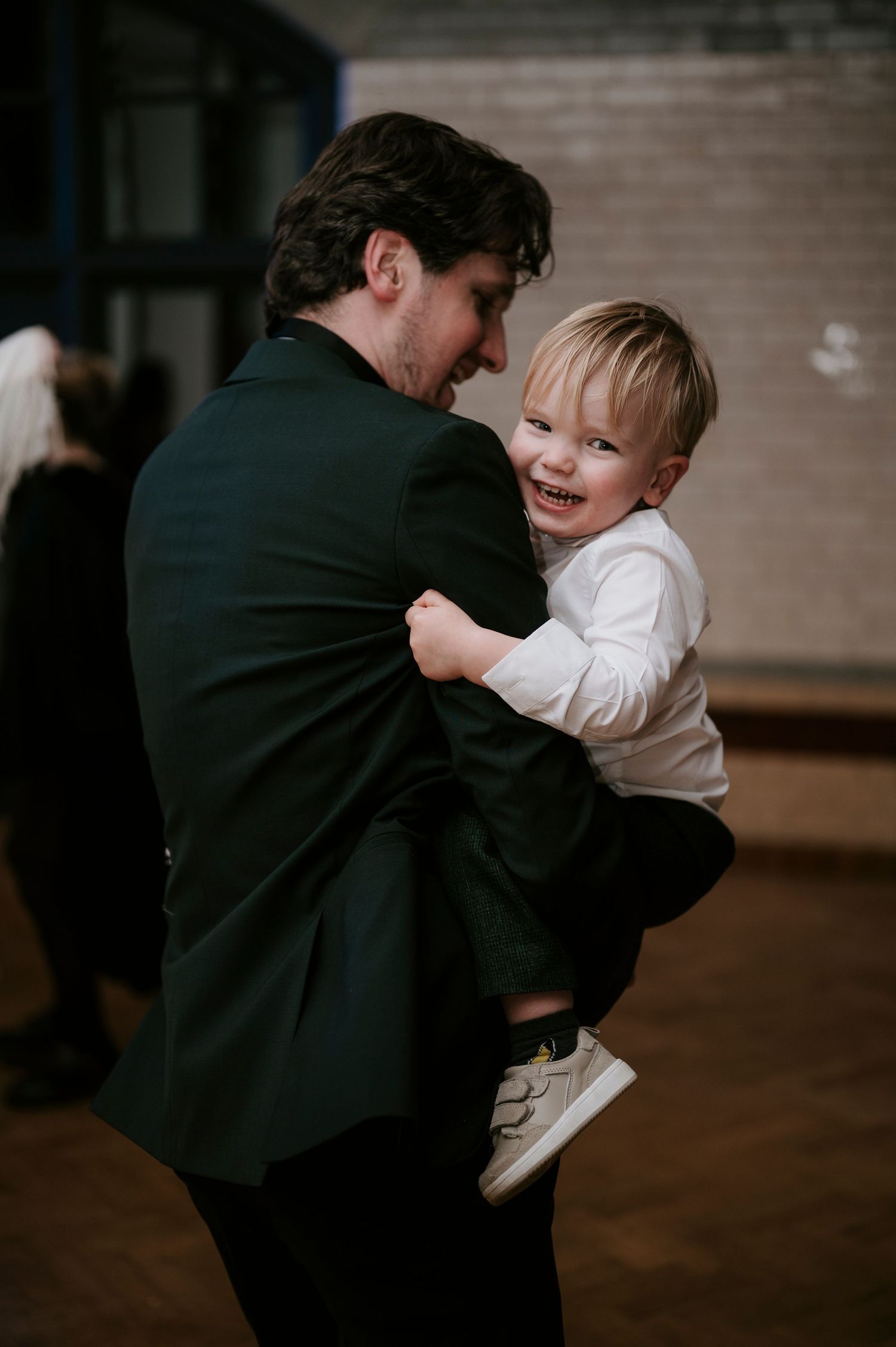 A heartwarming moment between an adult in formal wear and a smiling child at a celebration.