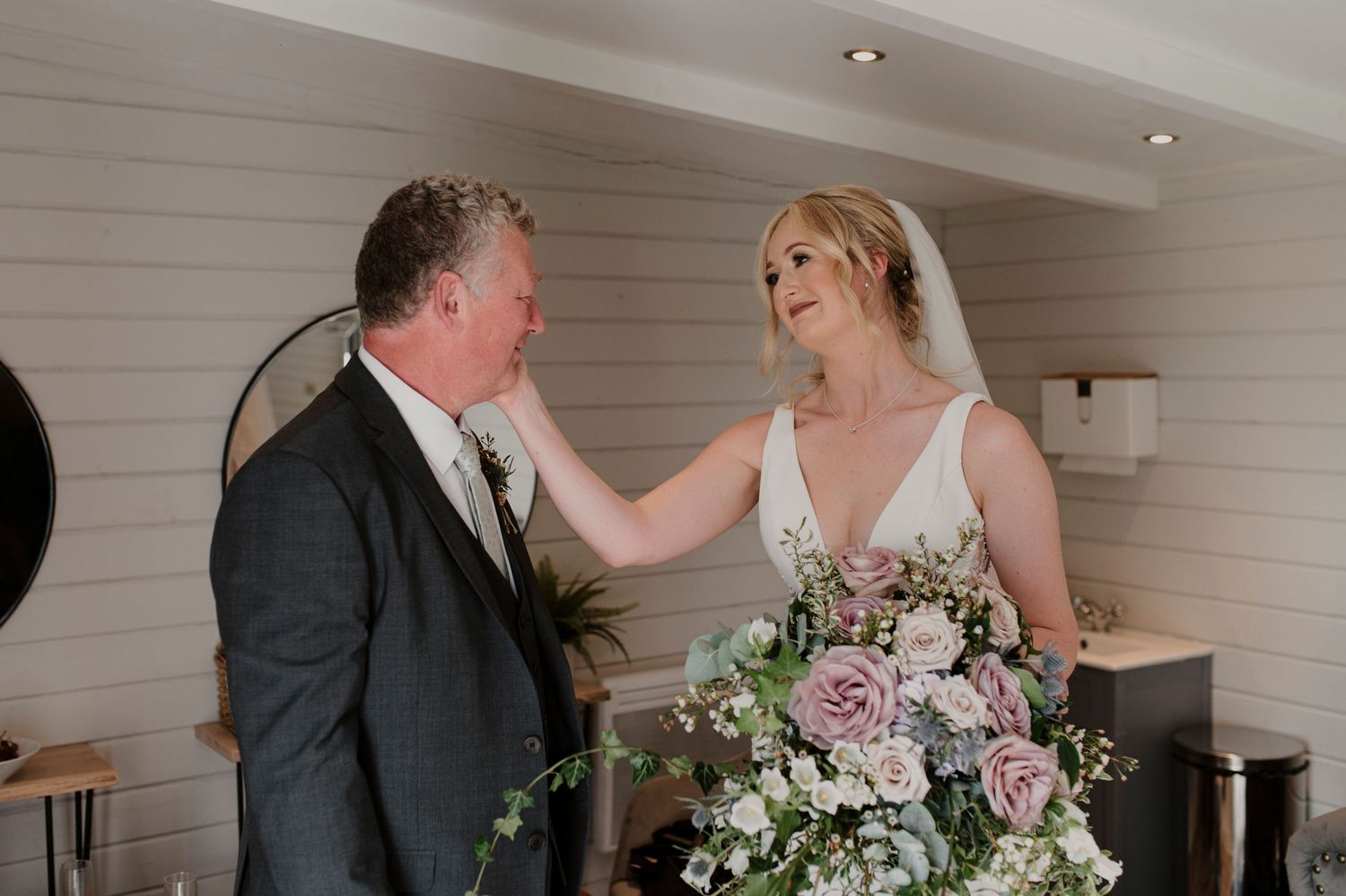 A couple shares a romantic moment during their wedding ceremony in a white-walled venue with soft lighting.