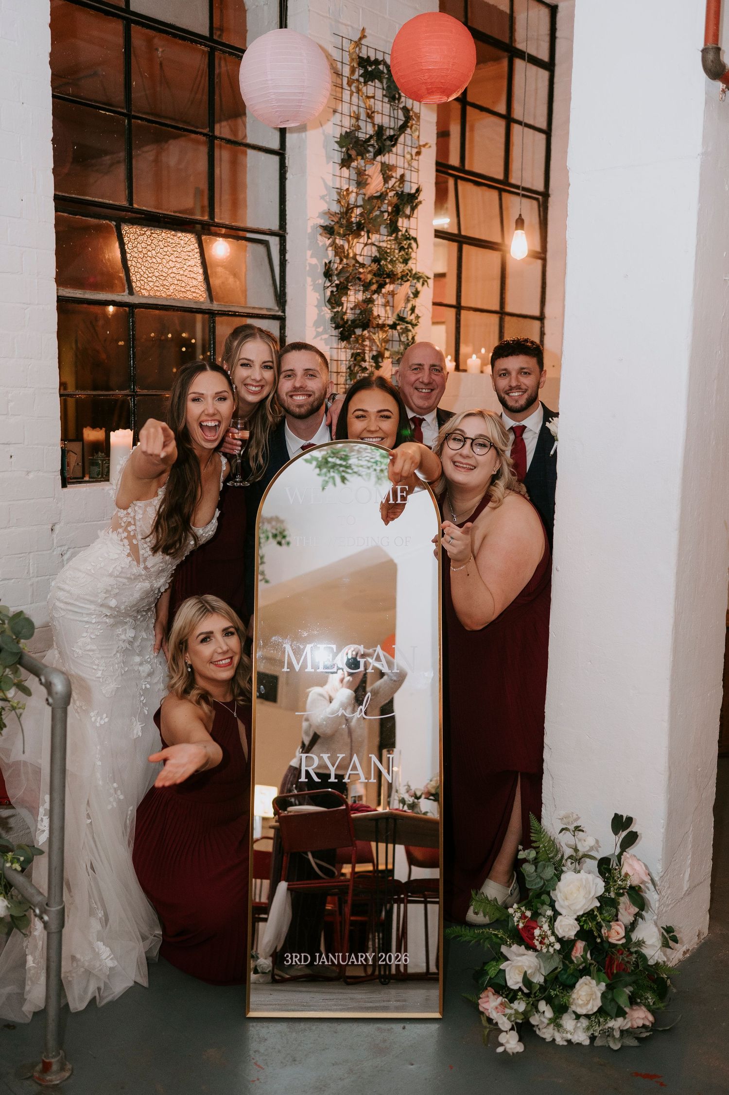 Wedding party posing with decorative mirror displaying Megan and Ryan 3rd January 2025 at elegant venue.