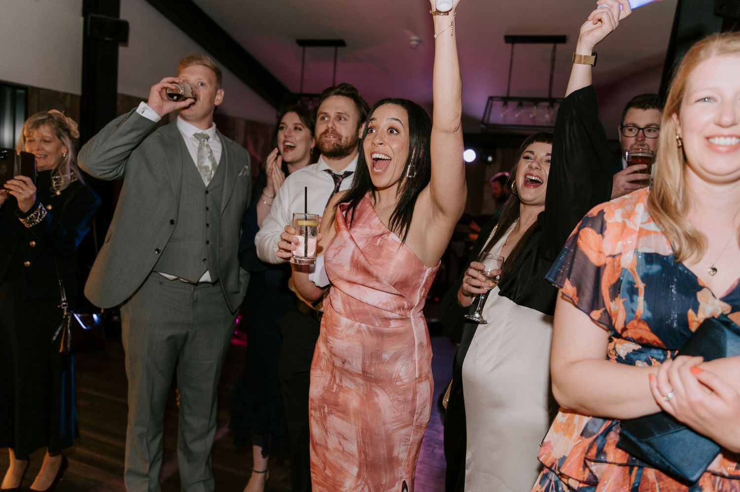 Wedding guests dance and celebrate on a crowded dance floor during an evening reception.