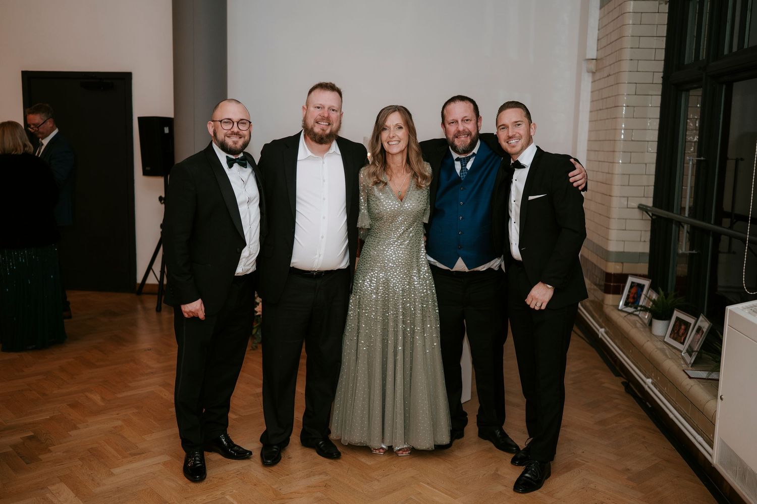 A group of formally dressed guests pose together at an elegant indoor event venue.