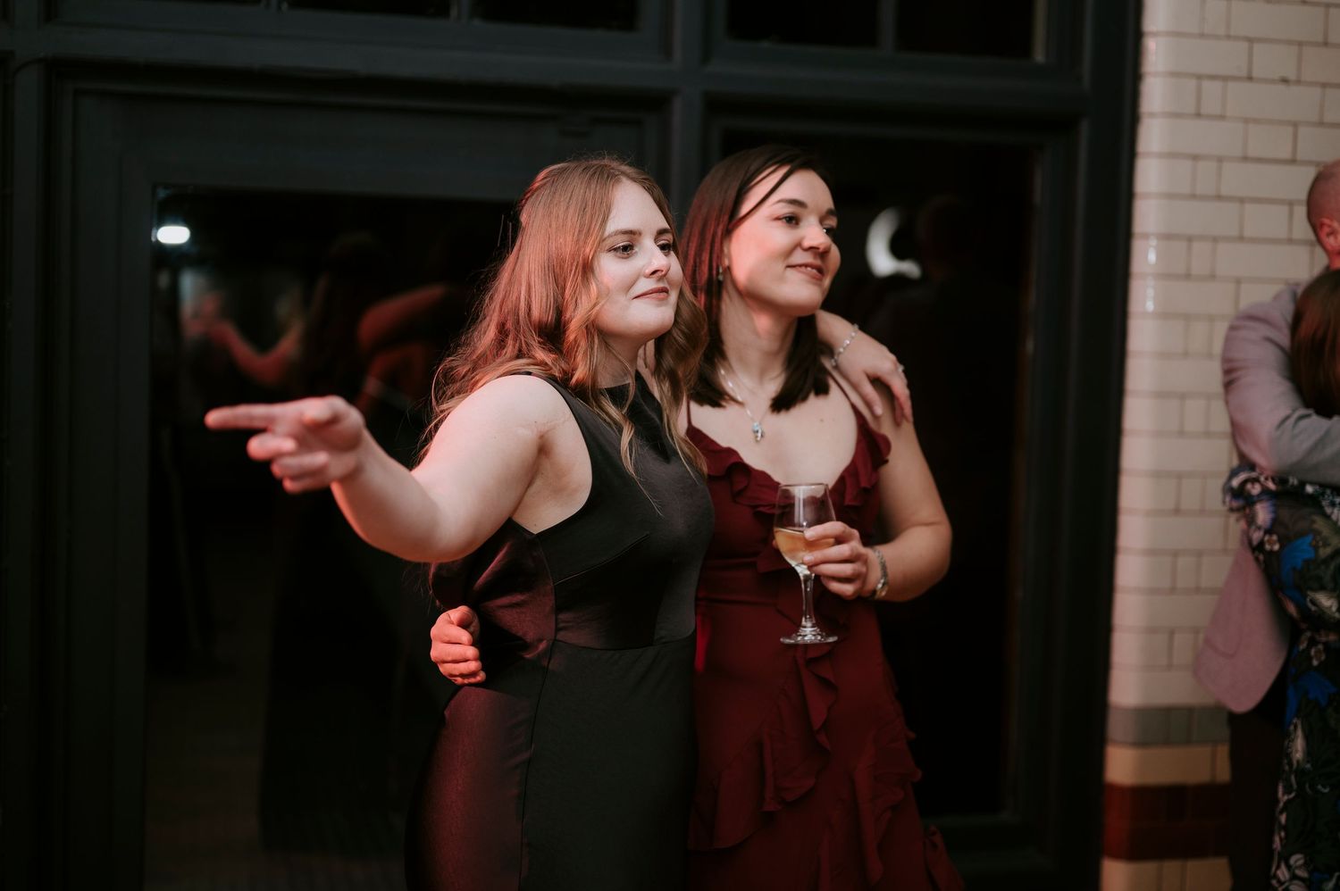 Wedding reception guests dancing and socializing in a modern venue with brick walls.