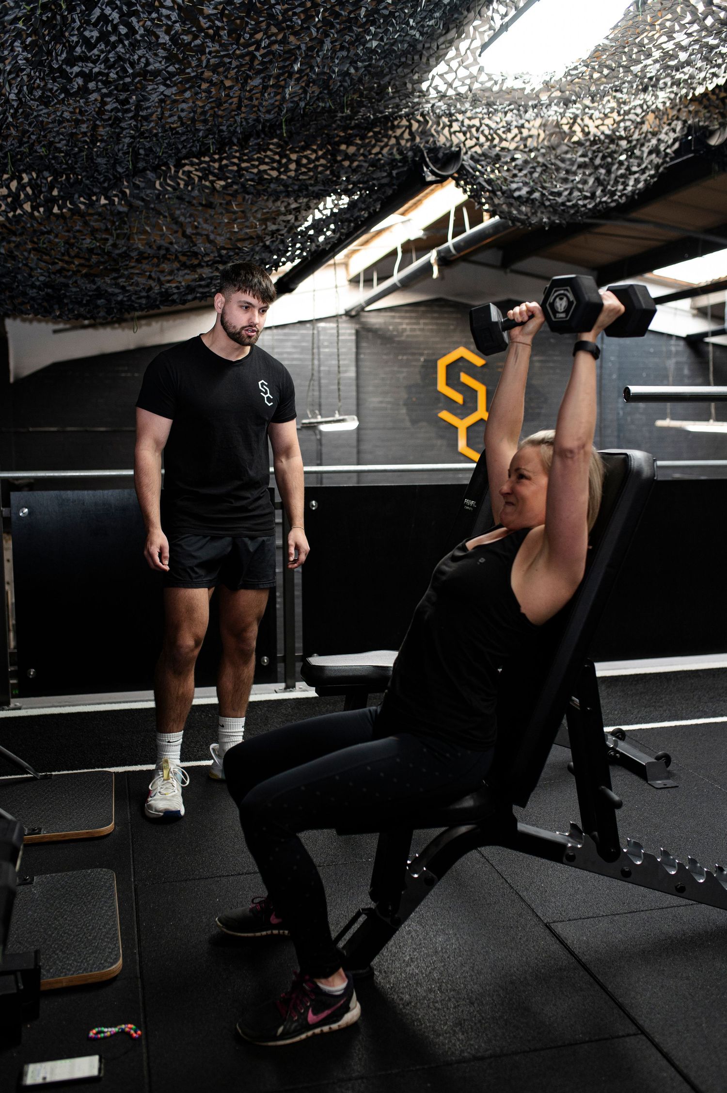 Series of weightlifting movements shown in sequence against dark gym background with rubber flooring.