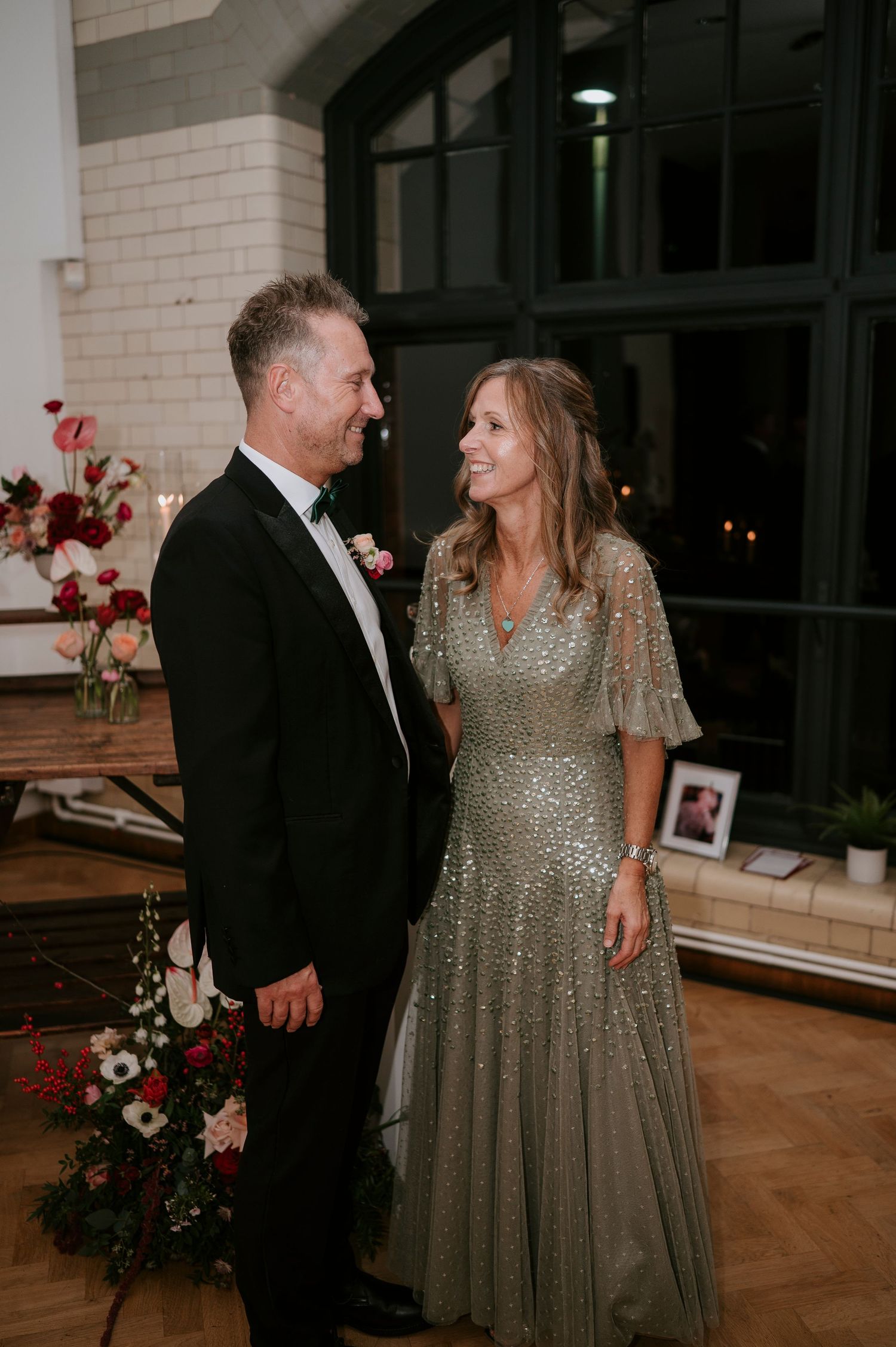 A couple shares an intimate dance moment as the woman wears a sparkling gold dress at an elegant event.