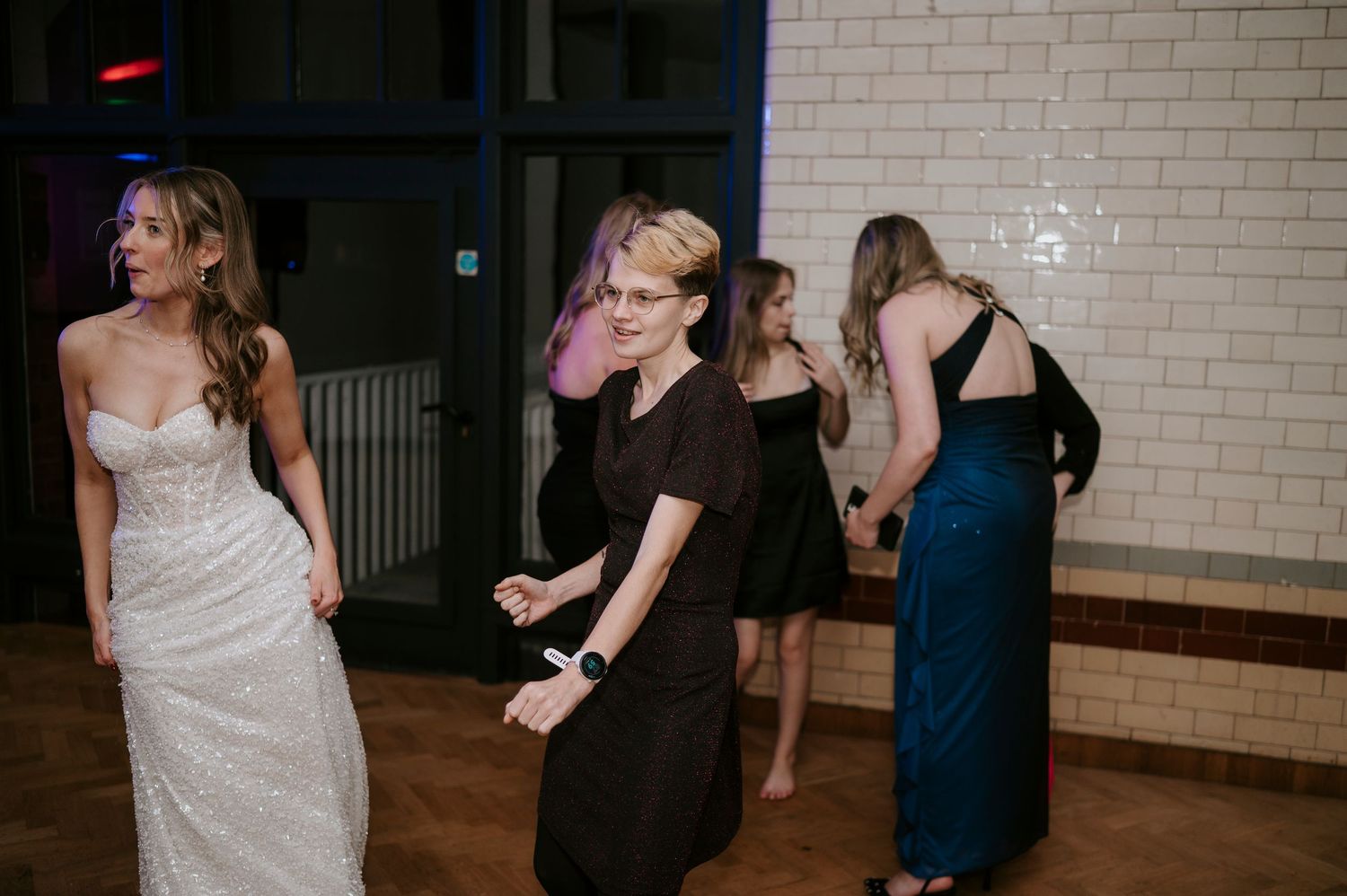 Wedding celebration with guests dancing energetically on wooden dance floor.
