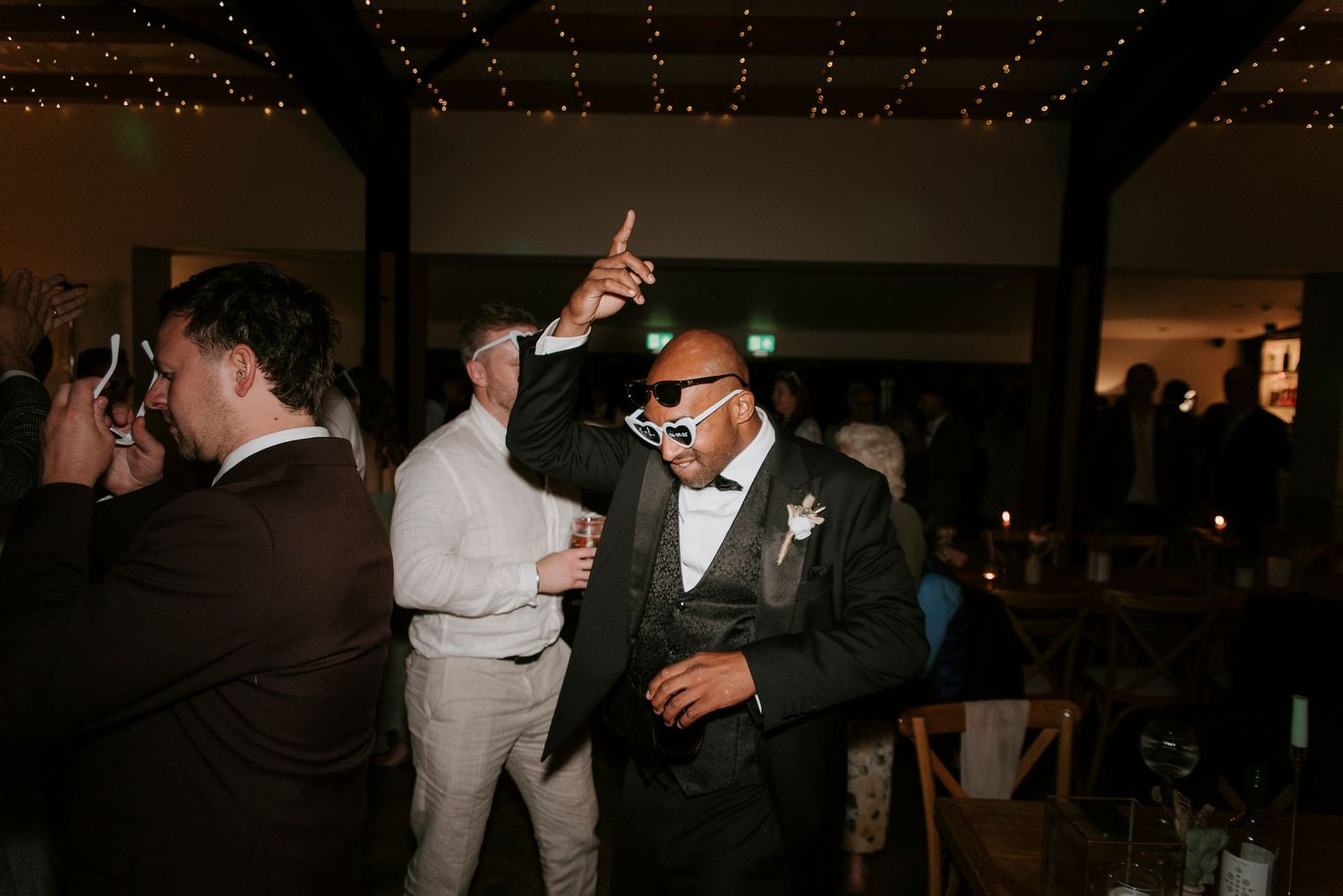 A group of people dancing and celebrating at an indoor party or reception venue.