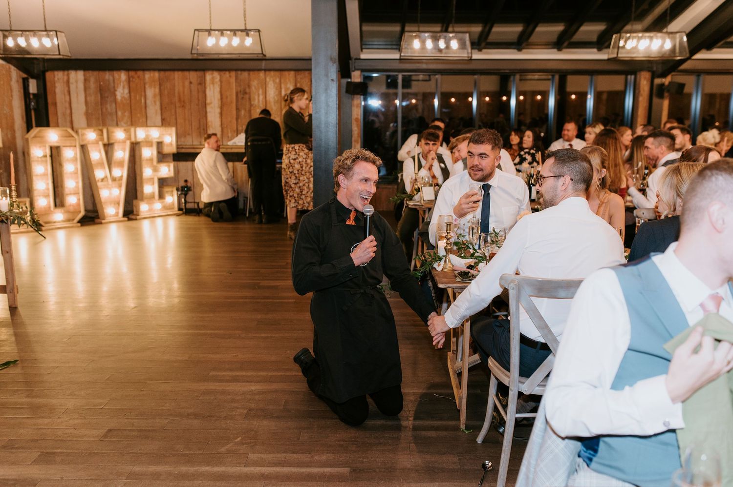 Wedding reception guests dancing and celebrating on an illuminated dance floor at an elegant indoor venue.