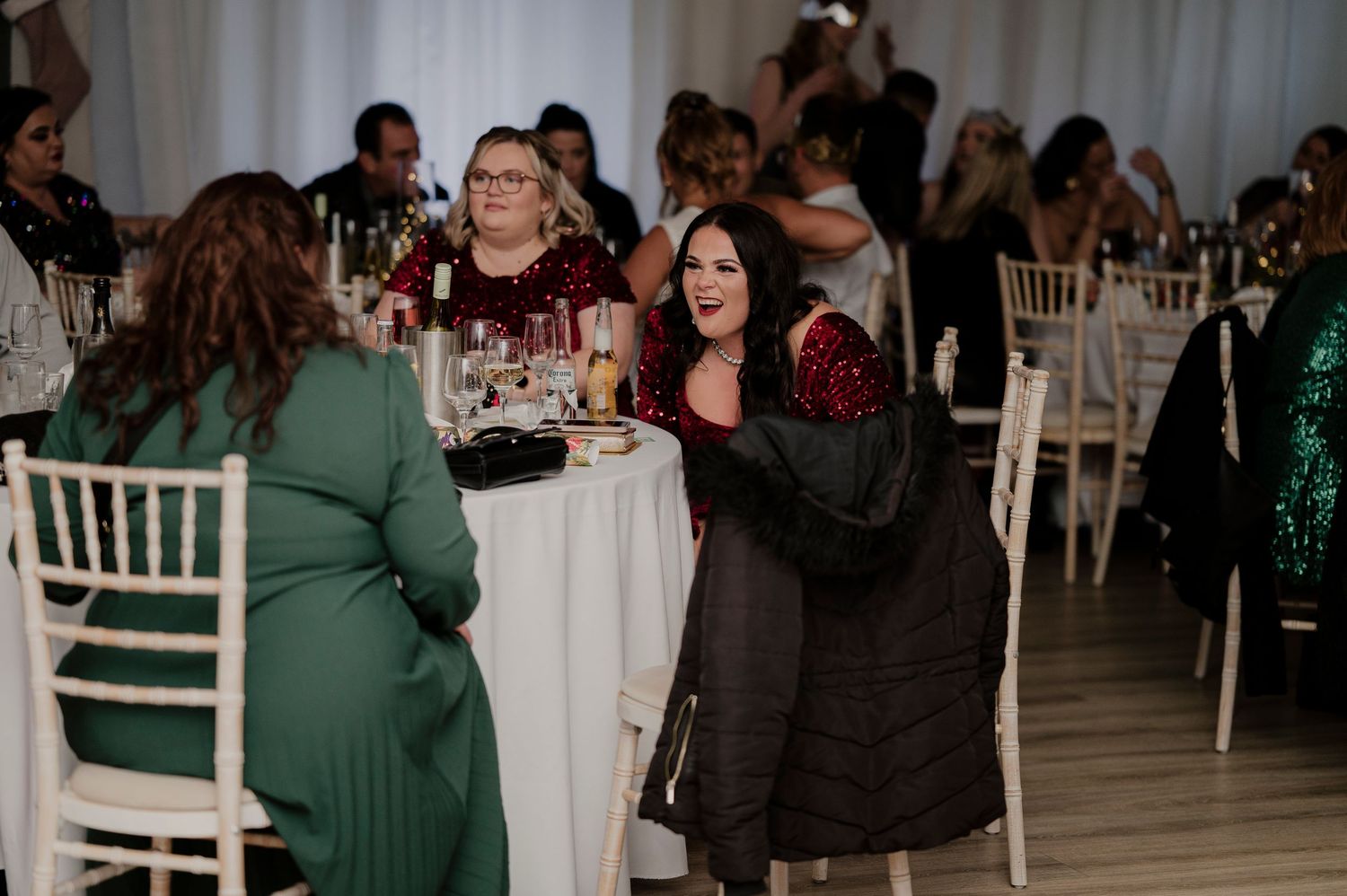 Wedding reception guests seated at elegant white tables in a banquet hall with festive decorations.