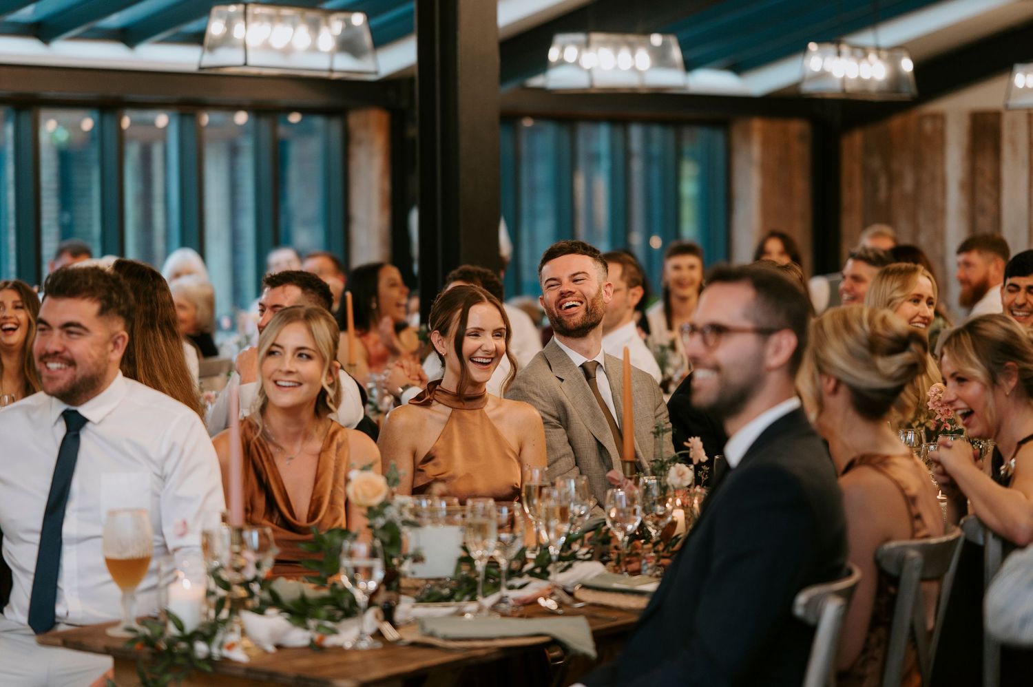 Wedding reception guests seated at long tables during dinner celebration.