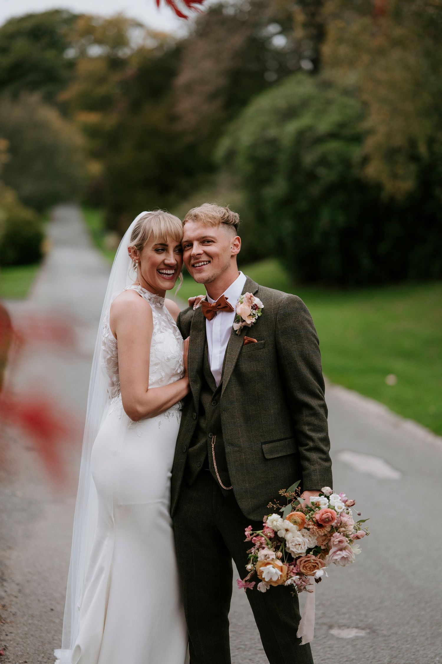 A happy couple shares joyful moments during their wedding celebration in an autumn outdoor setting.