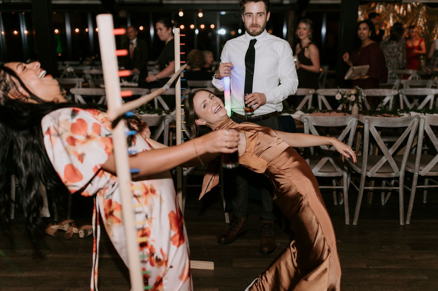 A dancer performs a graceful backbend move near a pole at an evening event while guests watch from nearby seating.