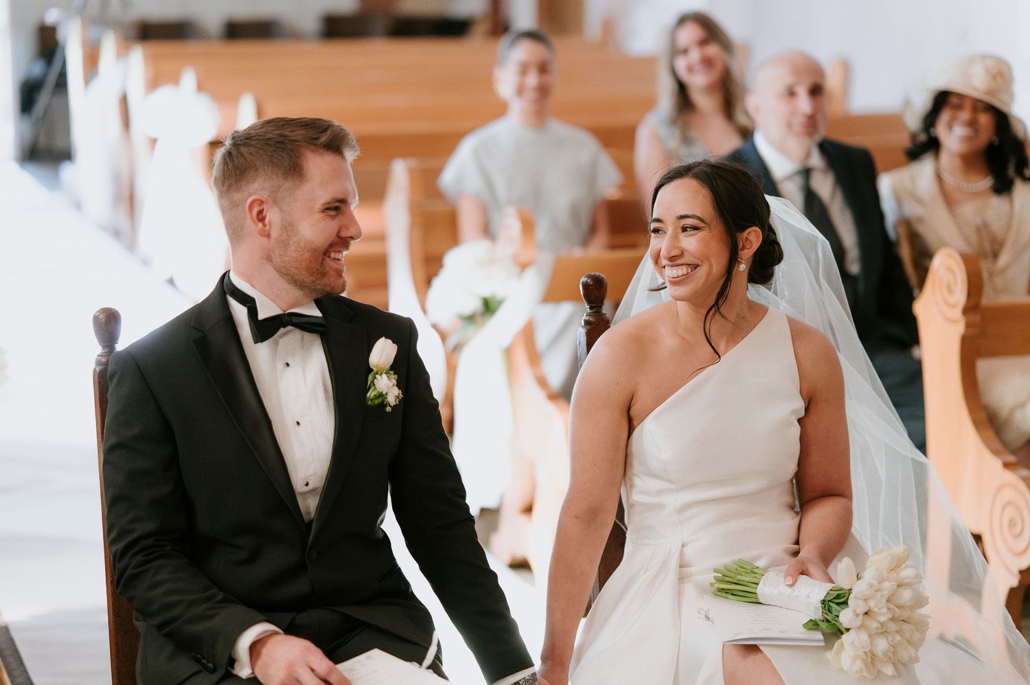 A wedding celebration with guests dancing and mingling in an elegant reception hall with warm lighting.