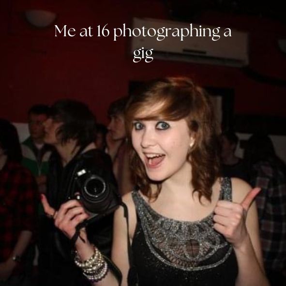 Young photographer in a sparkly black top holds a DSLR camera at a dimly lit music venue.