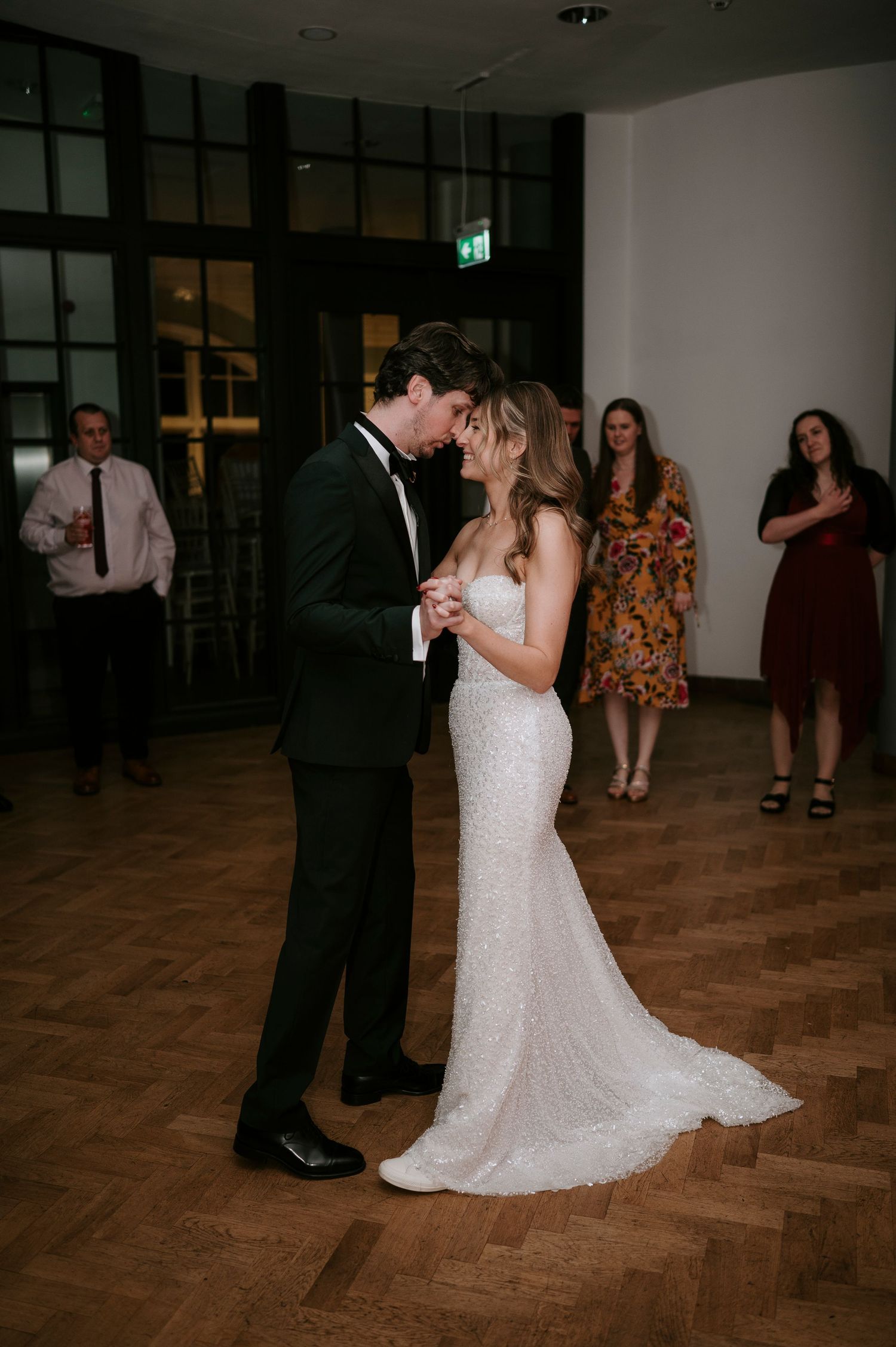 Couple sharing romantic dance on parquet floor at evening reception.