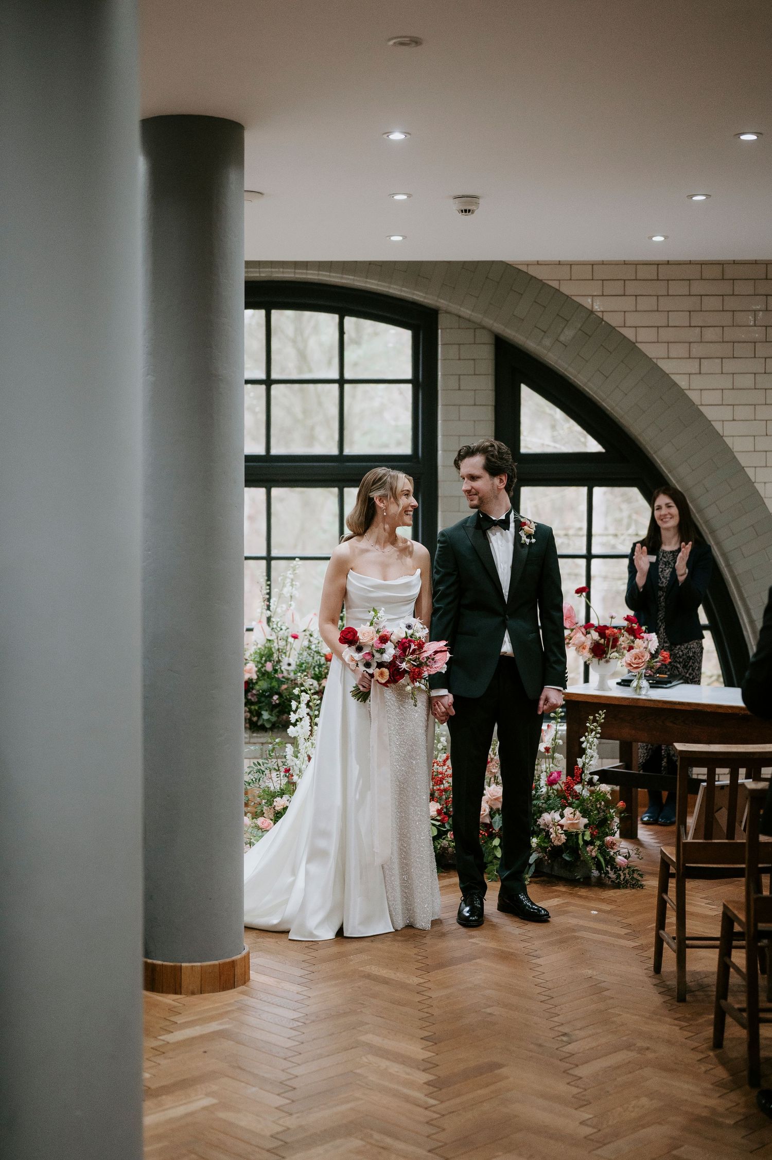 Wedding venue interior with cream brick walls, arched windows and herringbone flooring.