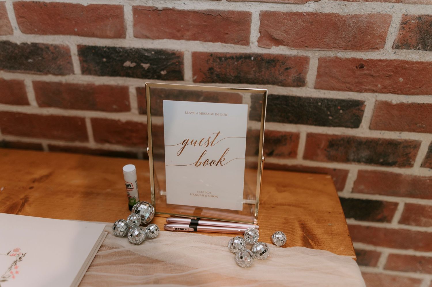A rustic brick wall backdrop with decorative table settings and metallic accents displayed on a wooden surface.