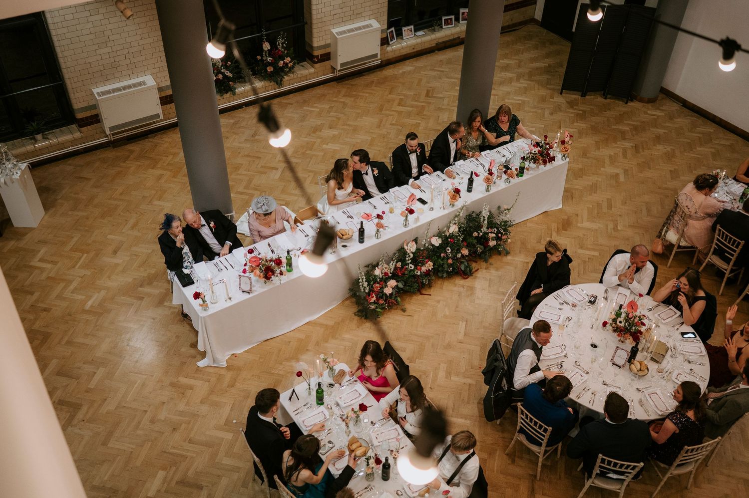 Overhead view of wedding reception tables arranged in long rows with white tablecloths and floral centerpieces.