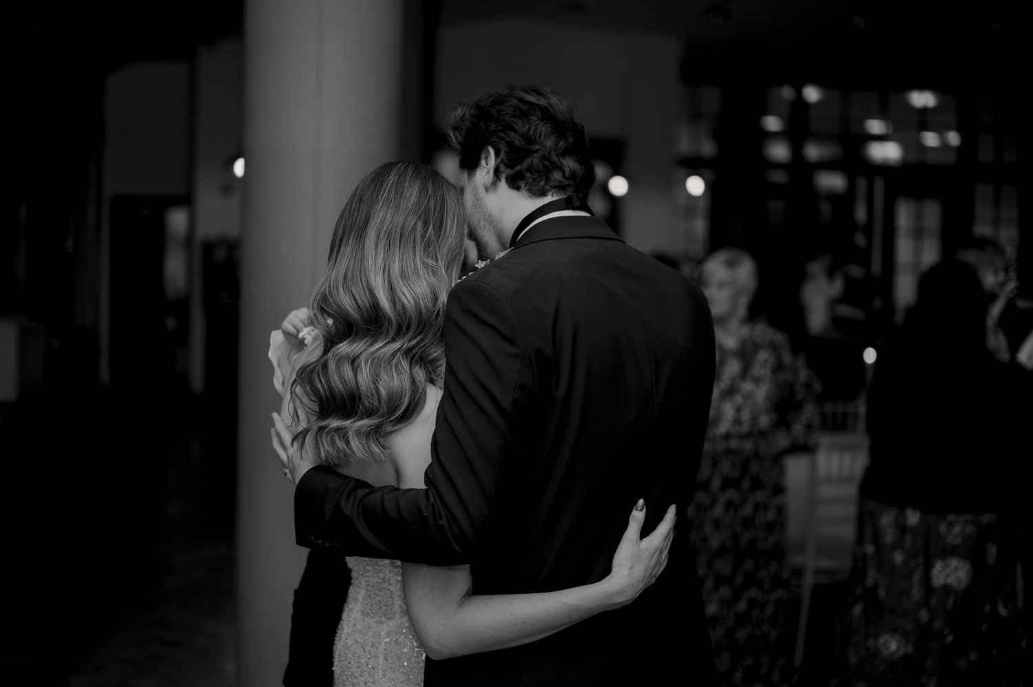A tender slow dance moment captured in black and white at an evening wedding reception.
