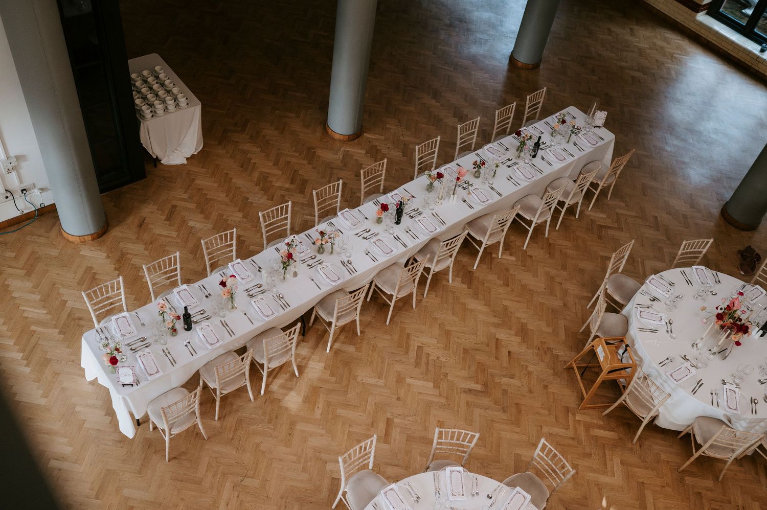 Overhead view of white chairs arranged in rows on a polished wooden floor for an event setup.
