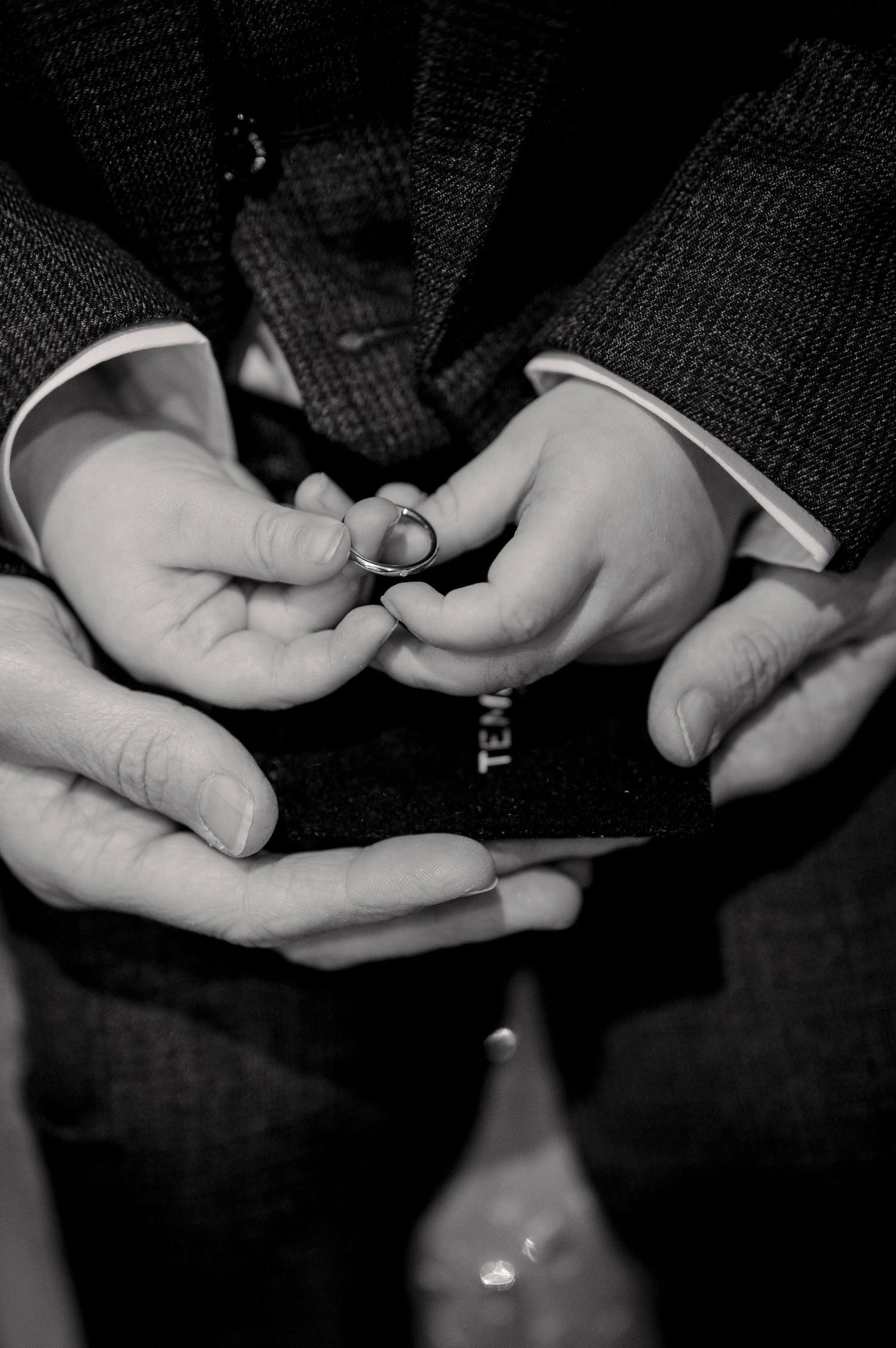 Black and white sequence of hands exchanging rings during a wedding ceremony.