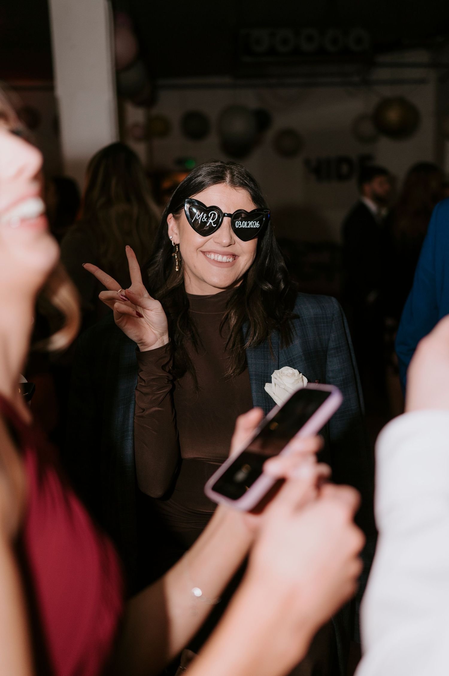 Wedding guest wearing Mr & Mrs novelty heart sunglasses poses at the reception party.