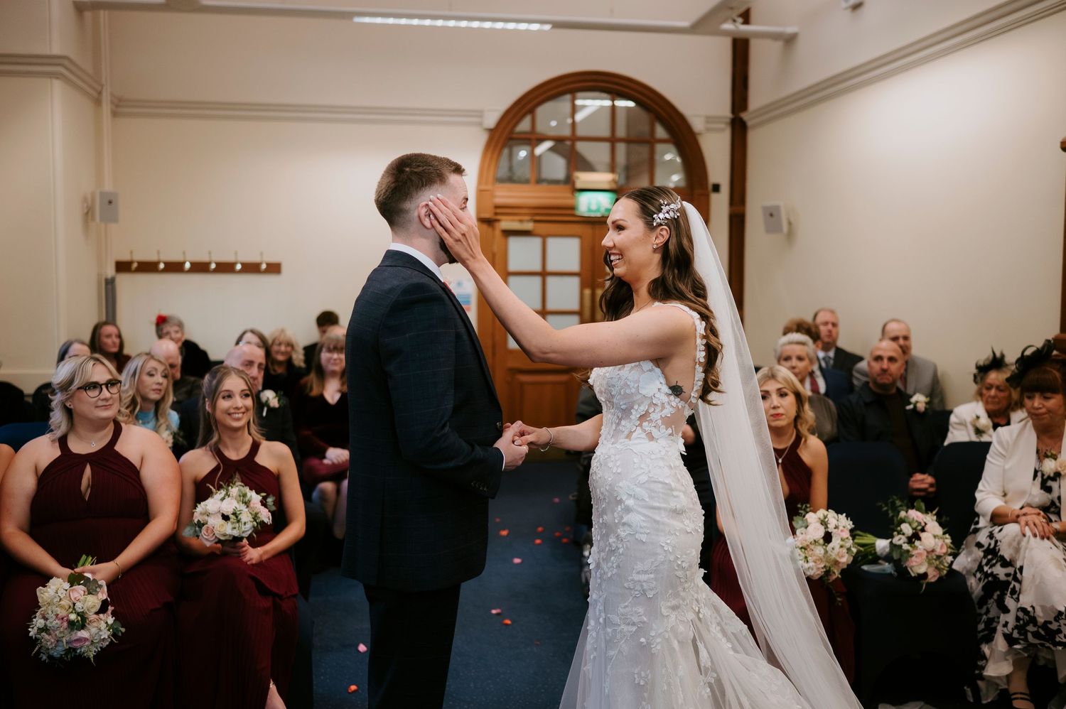 A joyful couple shares their first dance as newlyweds in a wedding ceremony surrounded by guests holding bouquets.