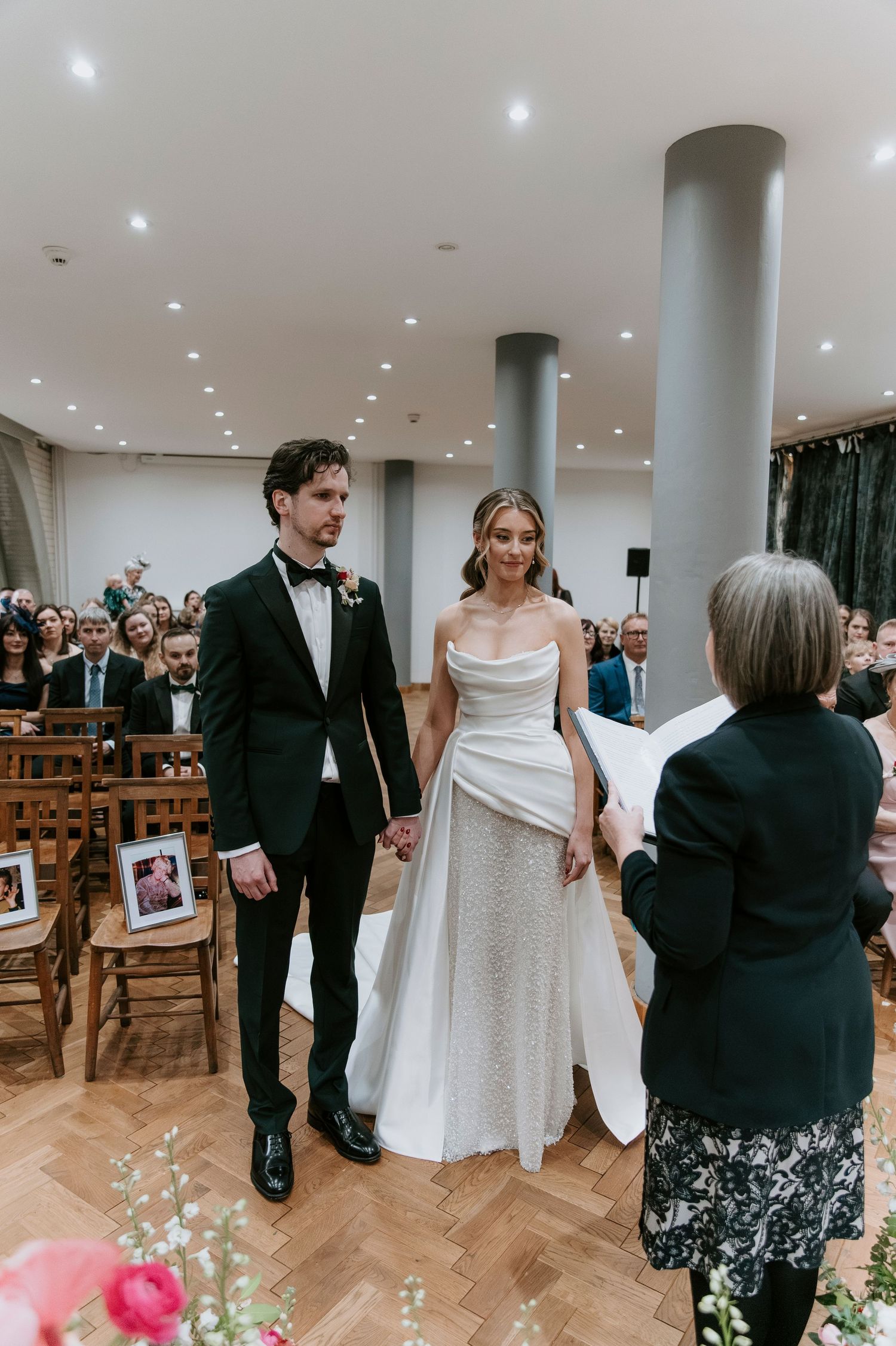 Wedding celebration in a bright room with columns where guests gather around the couple.