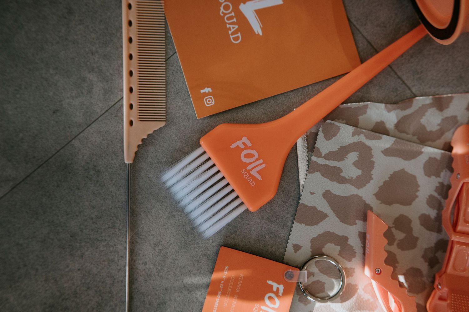 Orange and gray hair trimmer parts and attachments displayed on a dark textured surface.