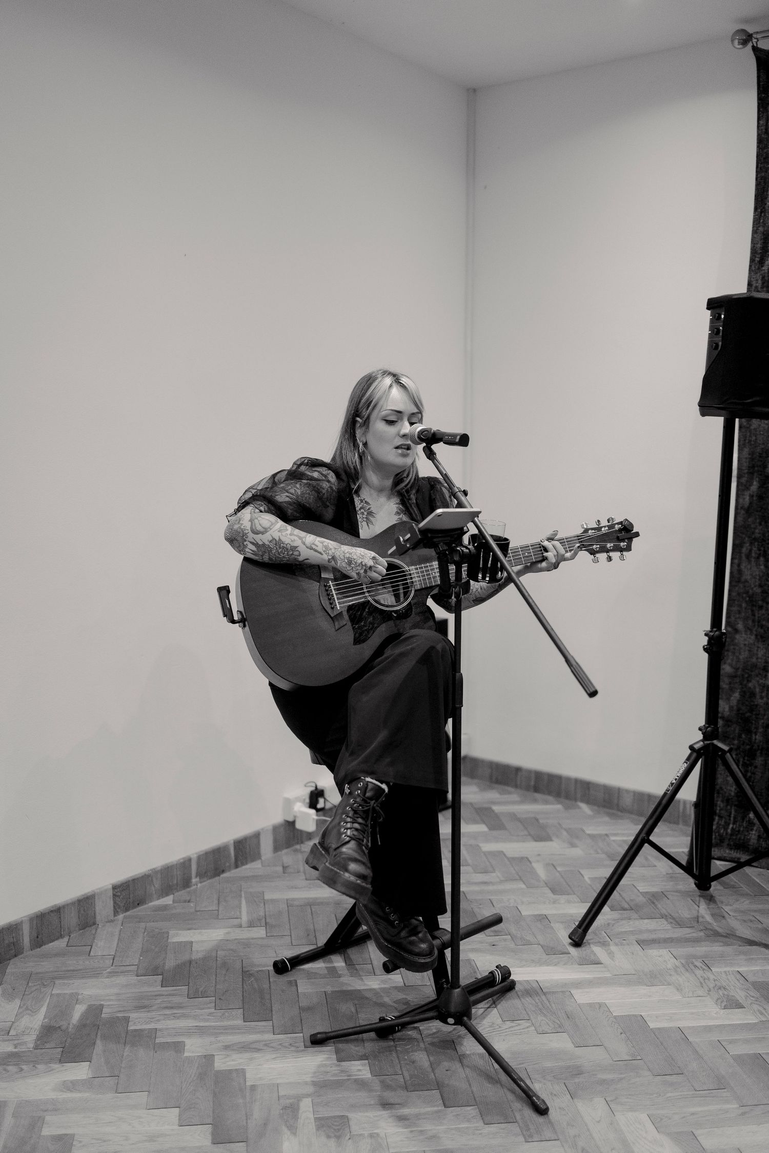 Black and white sequence of someone playing acoustic guitar while seated.