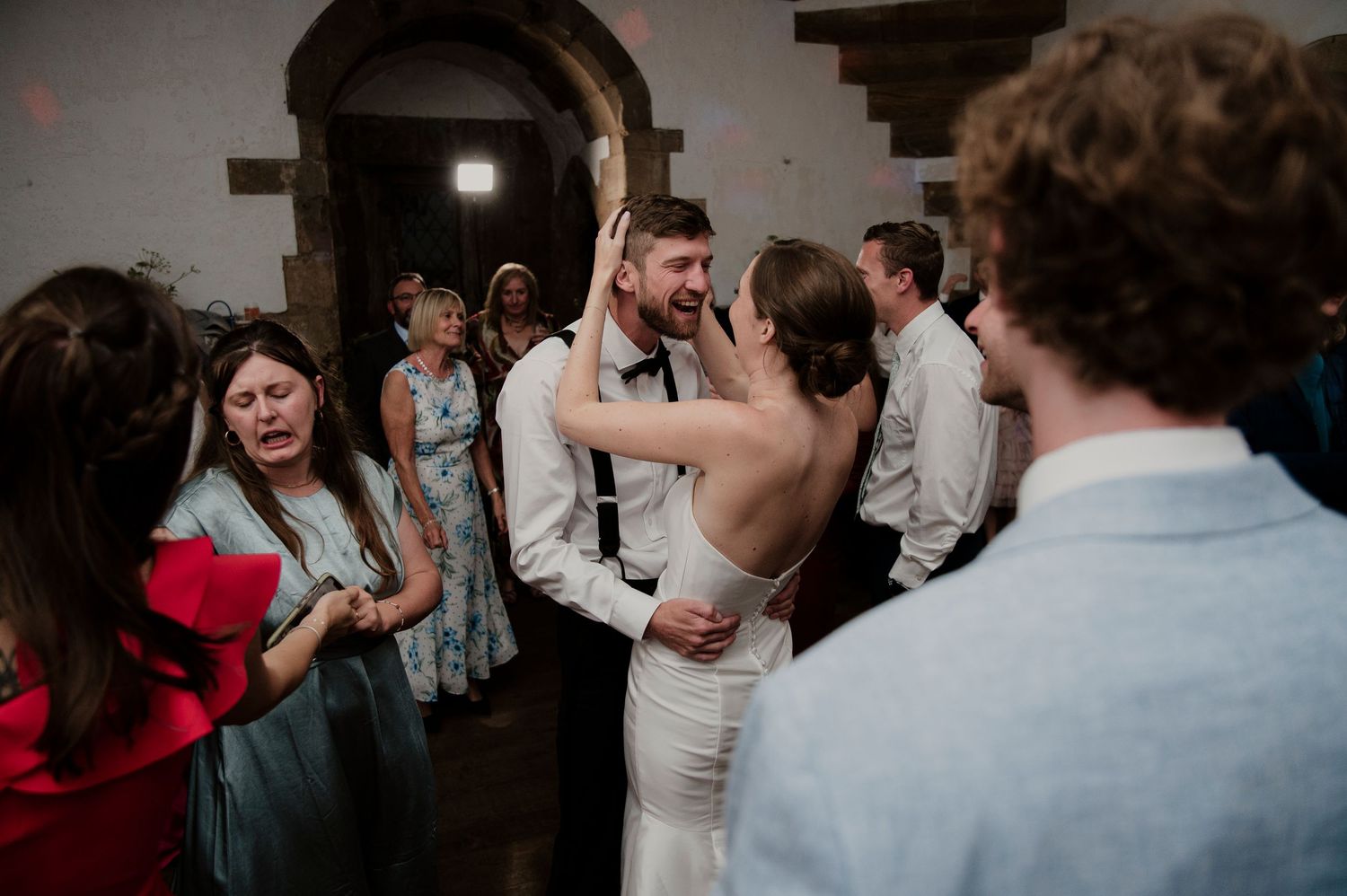 Wedding reception dance party with guests celebrating on a dimly lit dance floor.