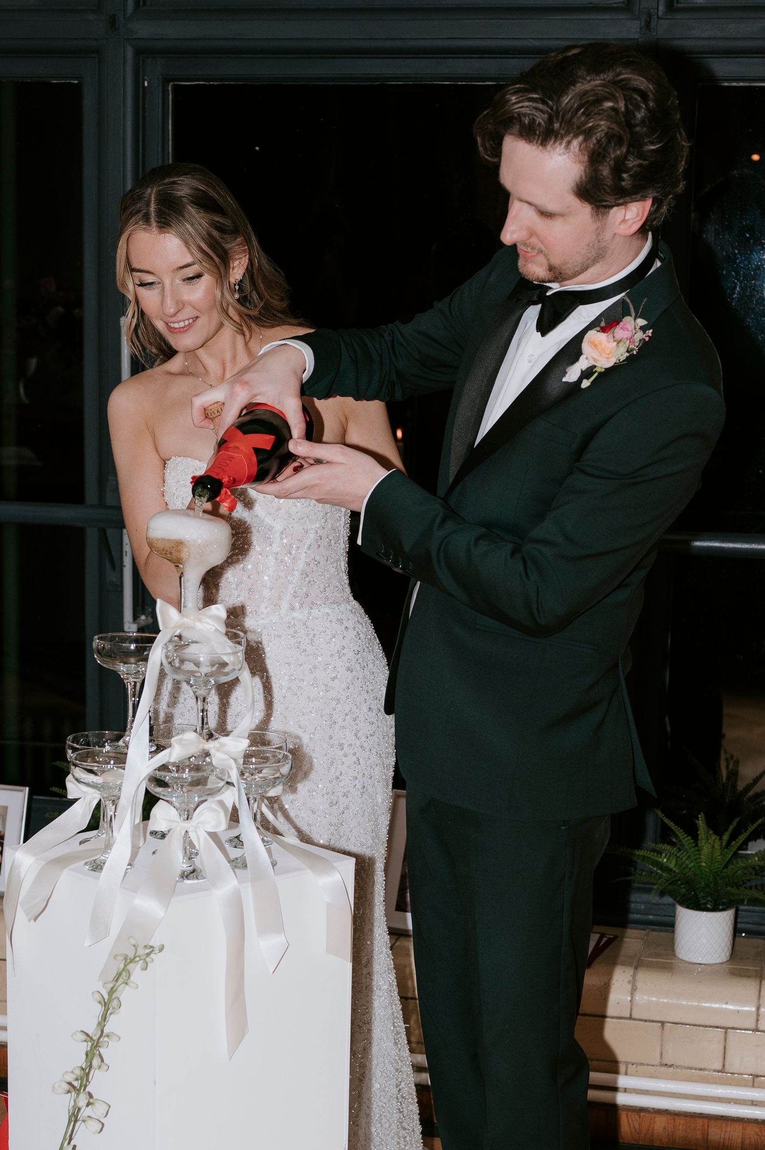Newlyweds perform their cake cutting ceremony at an elegant indoor reception.